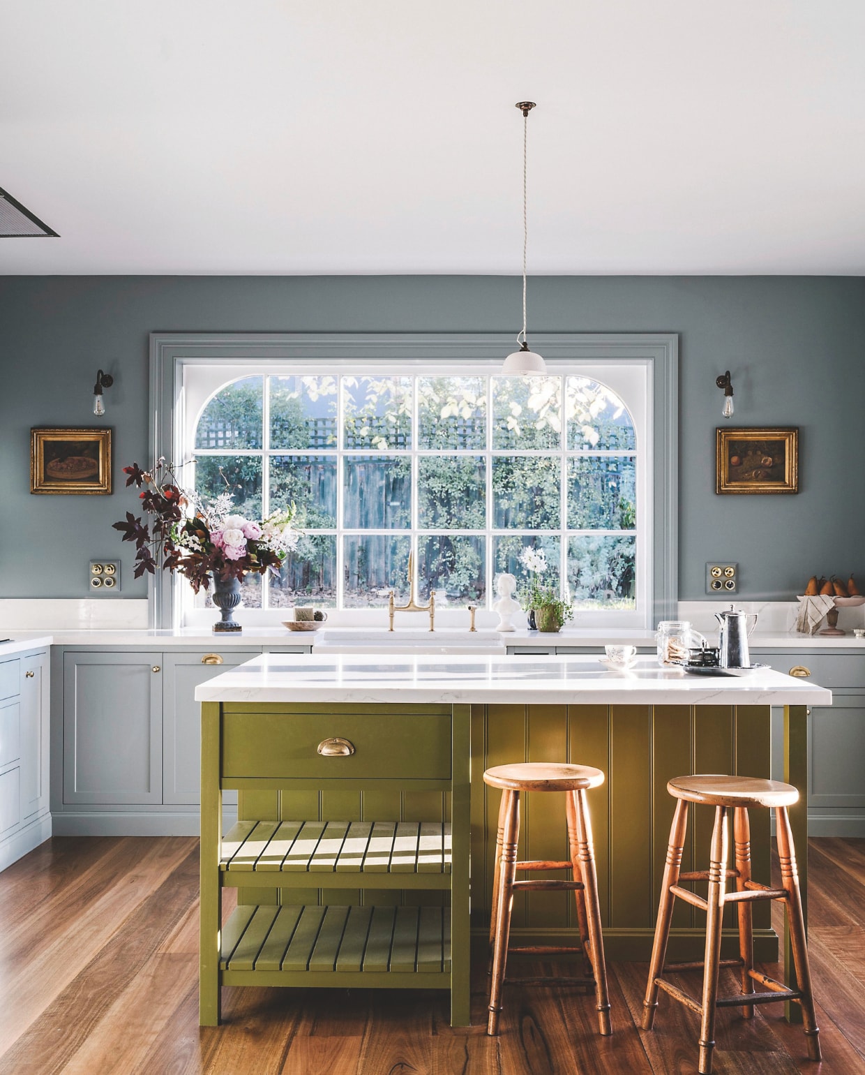 Keuken Custom Cabinets Tasmania. Gootsteen Shaws of Darwen. Kleur keukeneiland Moss en muurkleur Blue Spruce van Porter’s Paints. Barkrukken The Drill Hall Emporium. Vaas The Jardin Room. Olieverfschilderijen Anthea’s Attic. Hanglamp Devol. Wandlampen Dowsing and Reynolds. Koffiekan vintage. vtwonen landelijk 9-2025 | productie Living Inside | fotografie Marnie Hawson