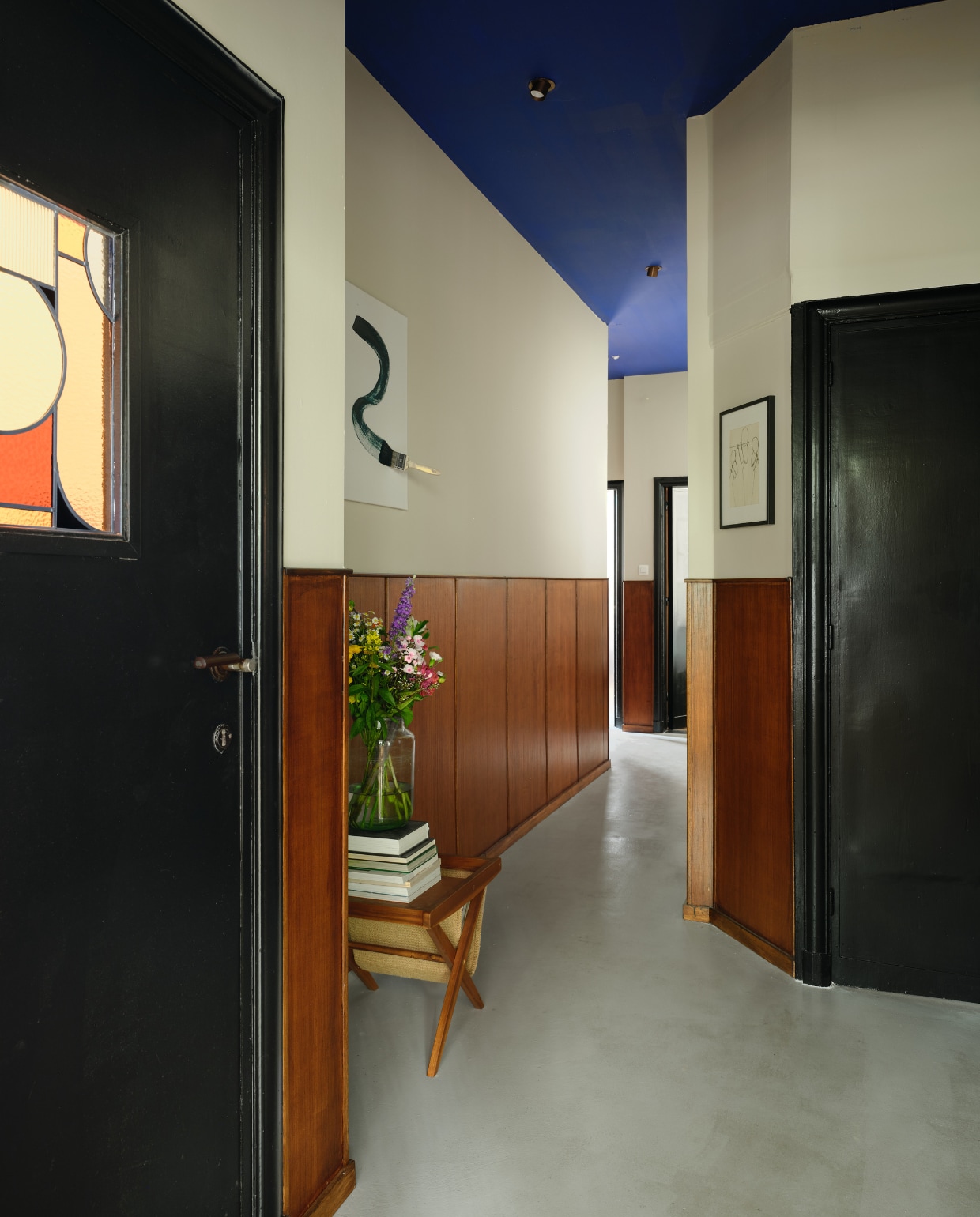 Vloer gegoten beton, glas in lood Hosanna, kunstwerk links Santicri, verfkleur plafond 100% Krokus van Flexa. Houten lambrisering zelf geplaatst. vtwonen 10-2025 | fotografie Mr. Frank