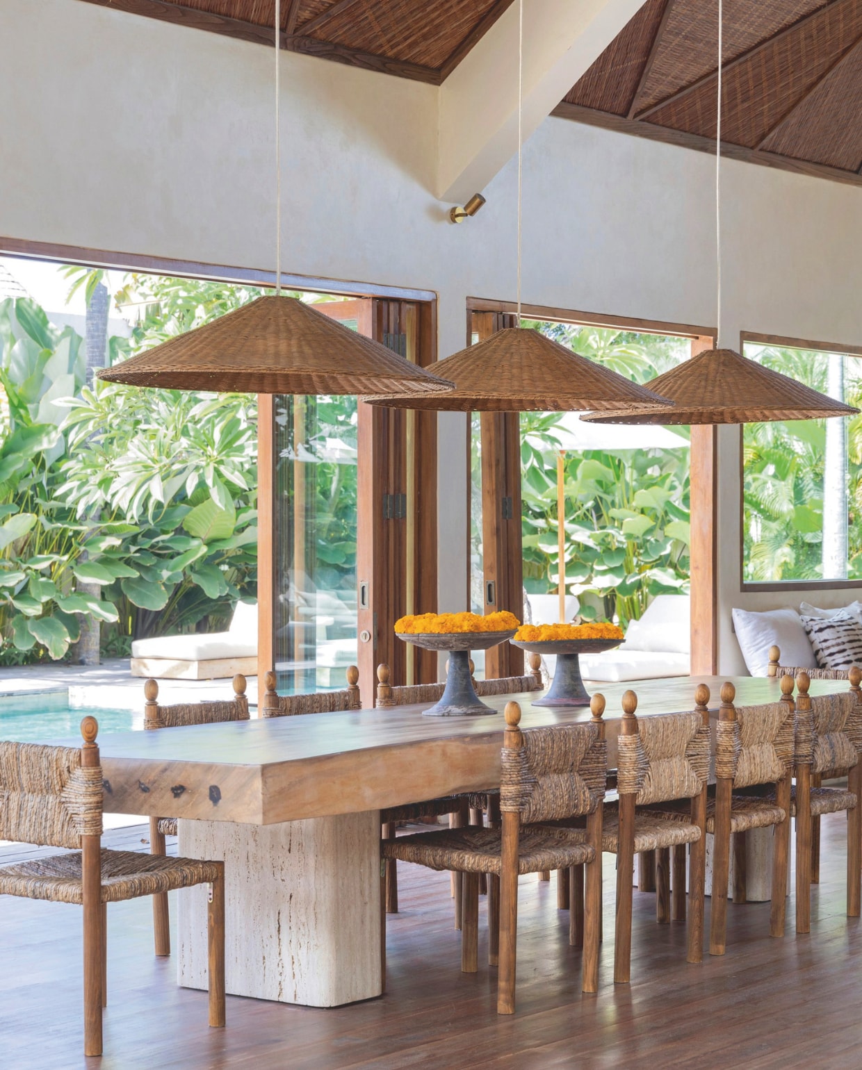 Het tafelblad bestaat uit één dik stuk teakhout. De tafel was al in de villa, Zoe liet er poten van travertin onder monteren. De inspiratie voor de stoelen kwam van antieke exemplaren van Charlotte Perriand. Rotan lampenkappen op maat gemaakt. vtwonen Landelijk 8-2025 | fotografie Sheila Man | tekstbewerking Marie Masureel