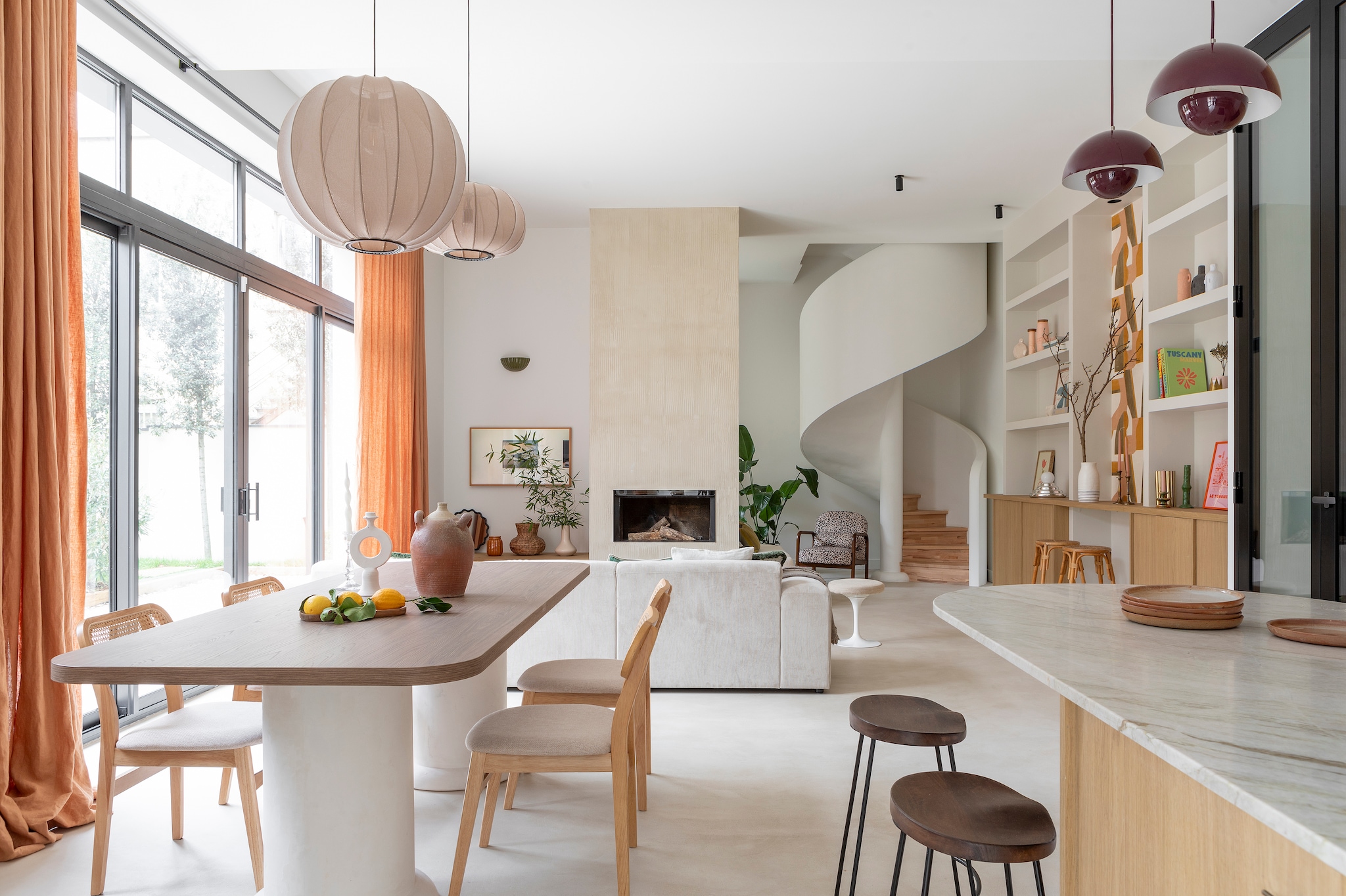 Bank Westwing. Kussen met patroon Jules Pansu. Kussens en gordijnen Élitis. Eettafel en opbergmeubels keuken ontworpen door Charlotte, uitgevoerd door B.i concept. Fles op tafel, slakom, houten plank en vaas met eucalyptus, geruit servies Les Puces du Canal. Kandelaars uit Marrakech. Stoelen Leivel van Sklum. Stoffen hanglampen Made by Hand. Spiegel The Socialite Family. Keukenfronten en planken Unilin. Aanrecht, werkblad keukeneiland en achterwand Taj Mahal graniet van Passion Granit. Kraan Treemme. Krukken Sklum. Witte wandlampen, Selency. Bruine kommen Søstrene Grene. Poster kreeft Poils Plumes Art. Hanglampen Flower Pot van &Tradition. Keukeneiland Tmlt. Kookplaat Elica.Ingebouwde ovens en koffiezetapparaat Aeg.  vtwonen 01-2026 | styling Marie Maud Levron | fotografie Pierrick Verny | productie AC Scoffoni