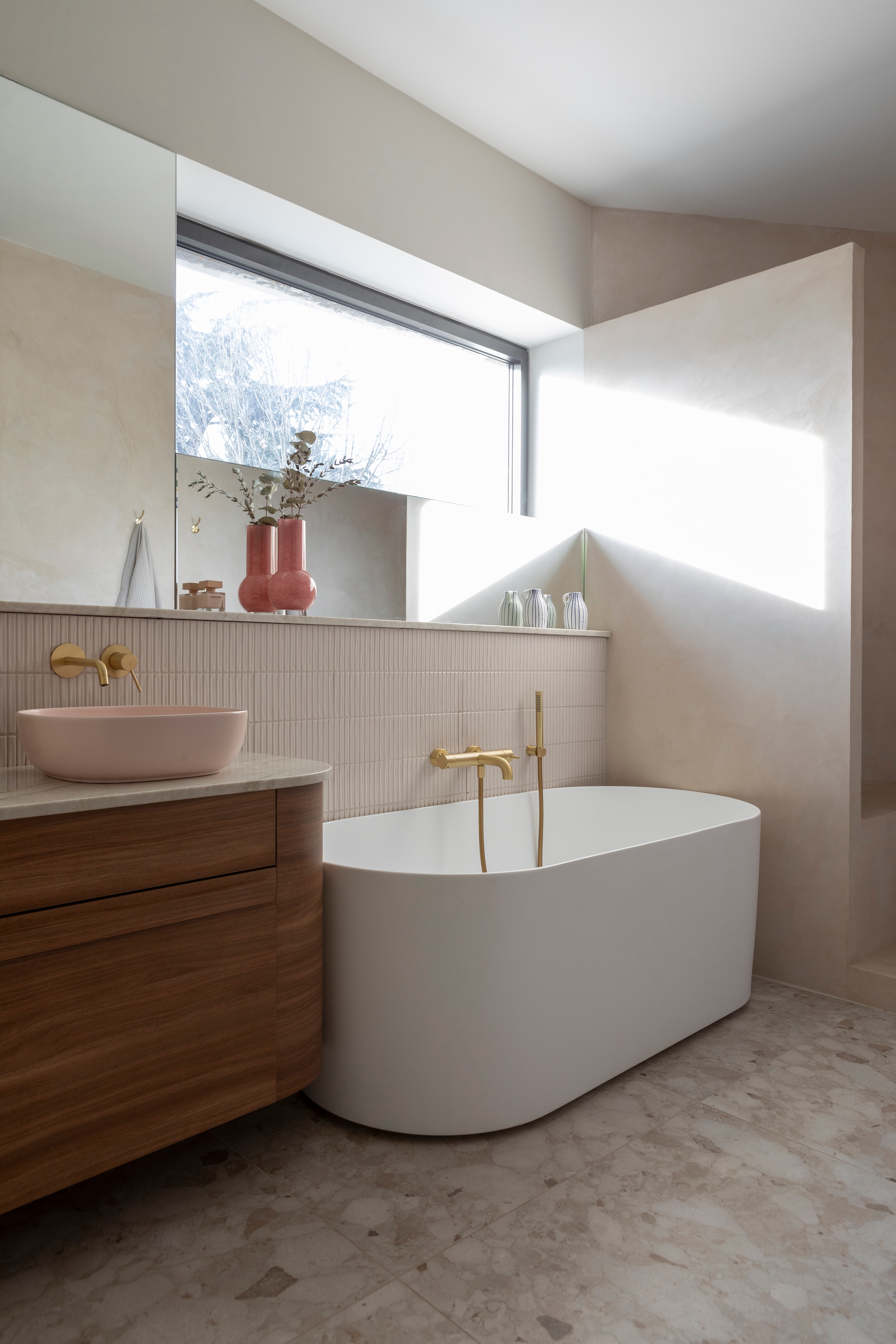 Vloertegel Sunset van Ceramica Sant’Agostino. Wandtegels Sweet Bars White van Wow design. Badkuip Tots. Kraan Treemme. Walnoothouten badmeubel op maat gemaakt met Unilin-panels. Wastafel Scarabeo via Richardson. Roze vaas Westwing. vtwonen 01-2026 | styling Marie Maud Levron | fotografie Pierrick Verny | productie AC Scoffoni