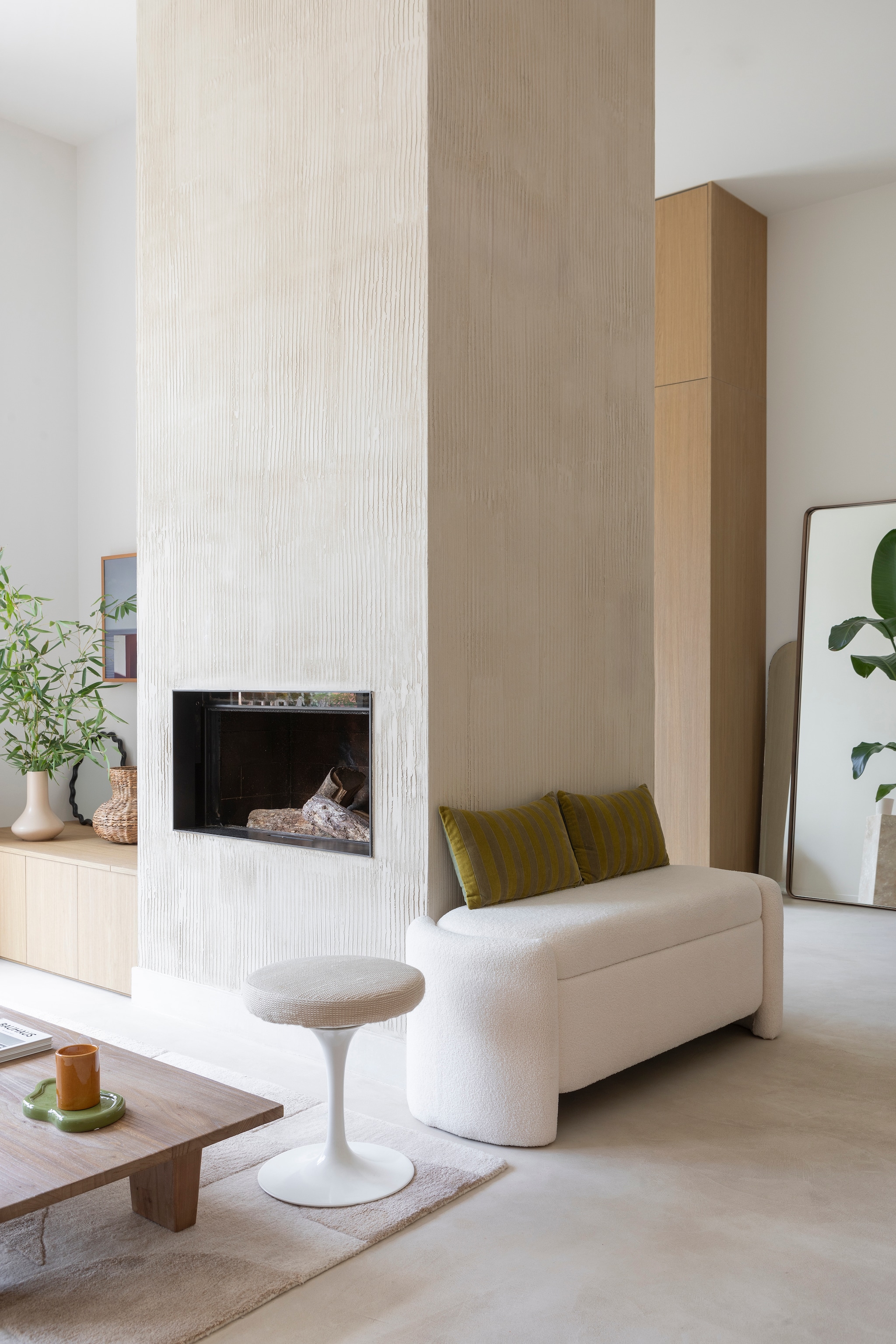Opbergbank Gliget via Amazon. Kussens HKliving. Vintage Knoll-kruk vlooienmarkt Les Puces du Canal. Betonvloer en schouw Tlmt. Muurverf Porcelaine van Ressource Peintures. Inzethaard Flammes et Créations. Kasten links Unilin. Vazen, spiegel en dienblad H&m Home. vtwonen 01-2026 | styling Marie Maud Levron | fotografie Pierrick Verny | productie AC Scoffoni