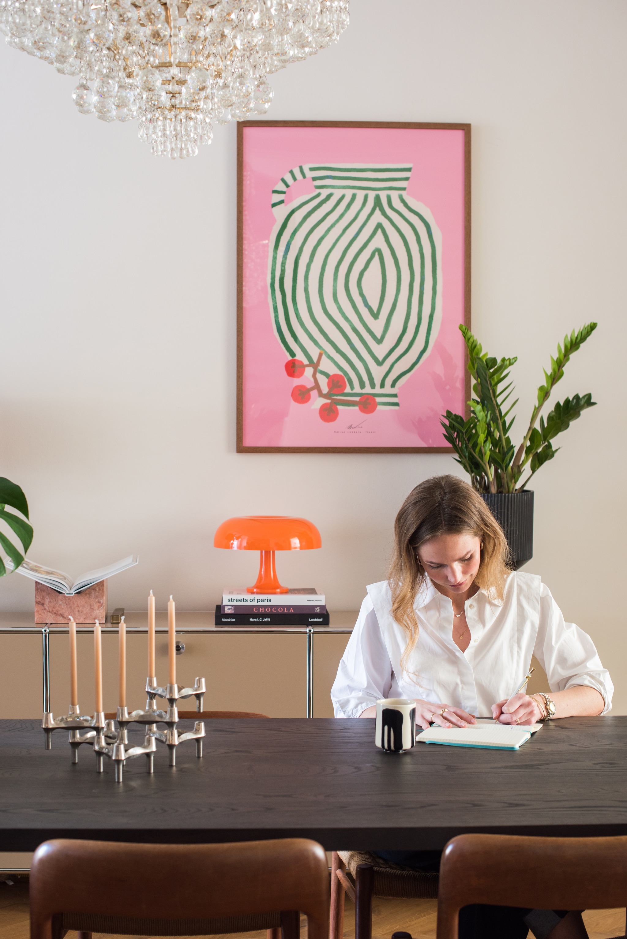 Muurverf Slaked Lime van Little Greene. Tafel Table du Sud. Poster The Poster Club. Hanglamp Marktplaats. Tafellamp Nessino van Artemide. Boekenstandaard gekregen. Plantenpot Karwei, Koffiekop Arket. Kandelaar Stoff Nagel.   vtwonen 01-2026 | styling Jasmijn Stegeman | fotografie Anke Leunissen