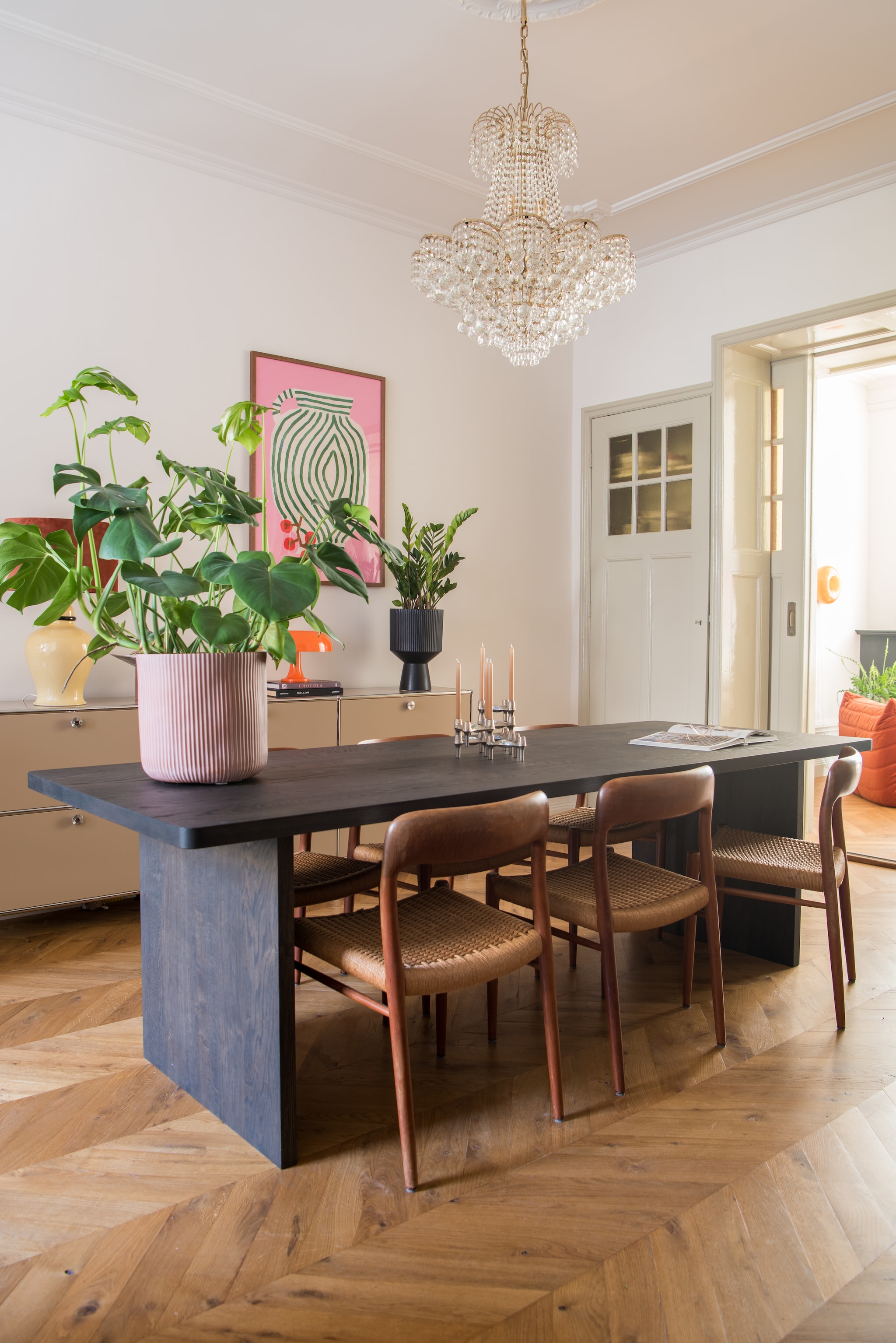 Muurverf Slaked Lime van Little Greene. Verf houtwerk Old White van Farrow & Ball. Vloer Hongaarse punt in naturel eiken. Eettafel Table du Sud. Stoelen Niels Otto Møller. Hanglamp Marktplaats. Dressoir Usm Haller. Plantenpotten Intratuin en Karwei. Kandelaar Stoff Nagel. Poster The Poster Club.  vtwonen 01-2026 | styling Jasmijn Stegeman | fotografie Anke Leunissen