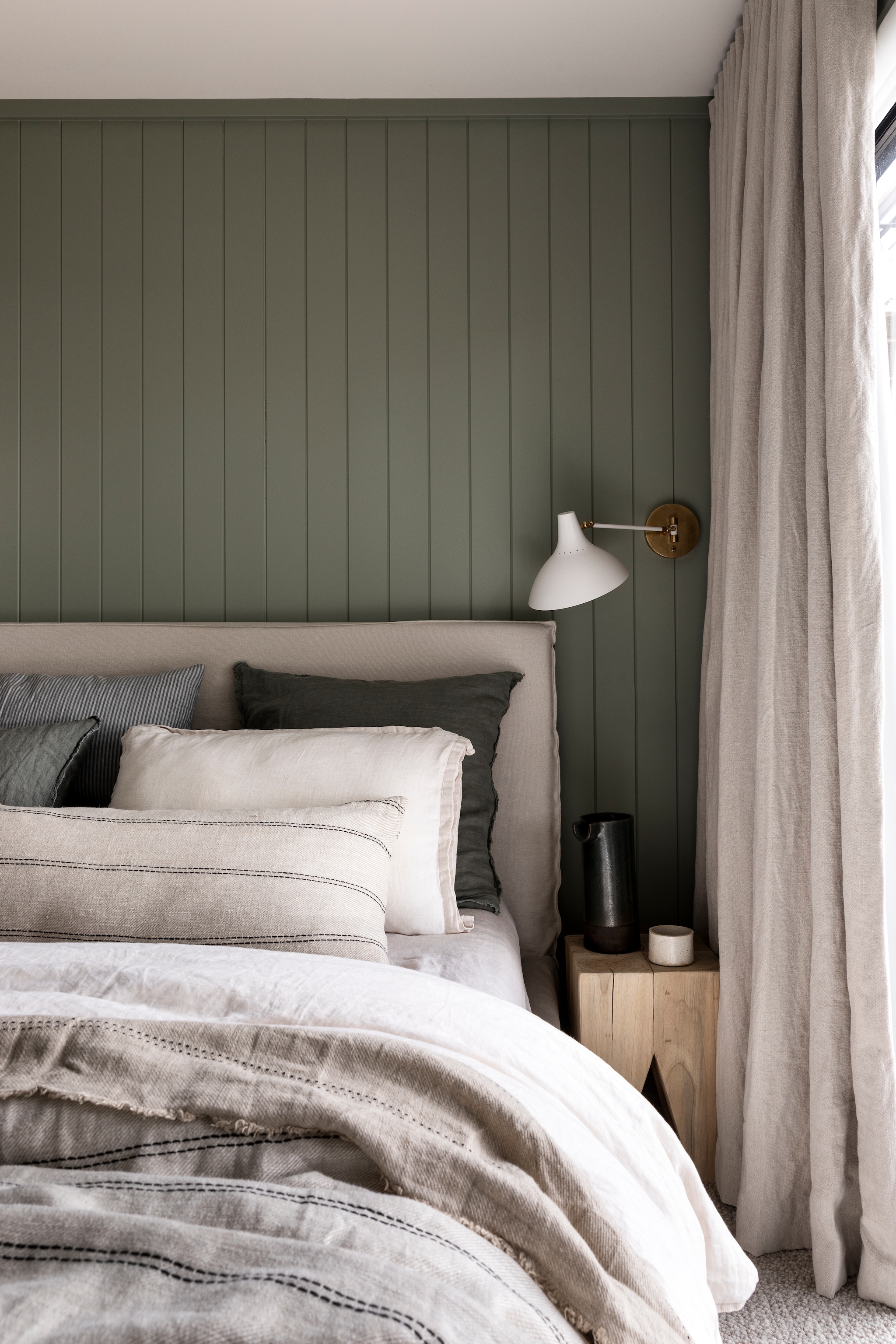 Wandbekleding EasyVj van Easycraft, kleur Olive Grove van Porter’s Paints. Nachtkastje Ocean + Stone. Gordijnen Stonewashed Linnen in Naturel van Westbury Textiles, gemaakt door Life By Shades. Wandlamp The Montauk Lighting Co. Bed Mcm House. Beddengoed Cultiver. vtwonen Landelijk 01-2026 | fotografie Martina Gemmola | productie Living Inside