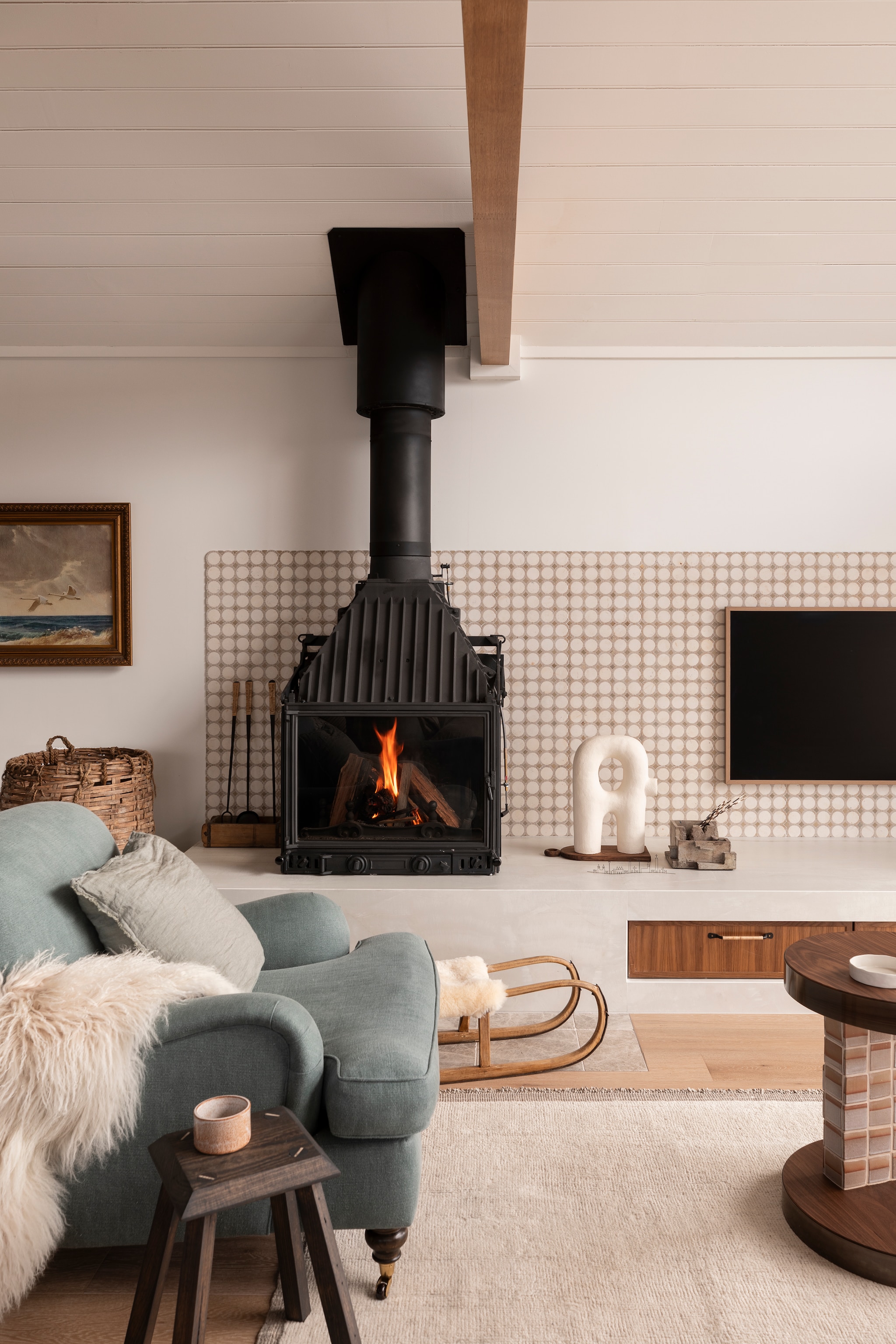 Kleur muur en plafond Half Watermark van Porter’s Paints. Open haard Radiante 700 3v van Cheminees Philippe. Beeld Stephanie Phillips Ceramics. Vloer Europees eiken in Smokey Grey, afwerking uv-olievan Woodcut. Wandtegels Custom Tunisia Serpentine Mosaic van Earp Bros. Maatwerk tv-meubel van notenhout en Marmi Bright Onxy van Artedomus. Maatwerk vloerkleed Halcyon Lake. Maatwerk fauteuil met stof van Westbury Textiles. Bijzettafel Chair Boi. vtwonen Landelijk 01-2026 | fotografie Martina Gemmola | productie Living Inside