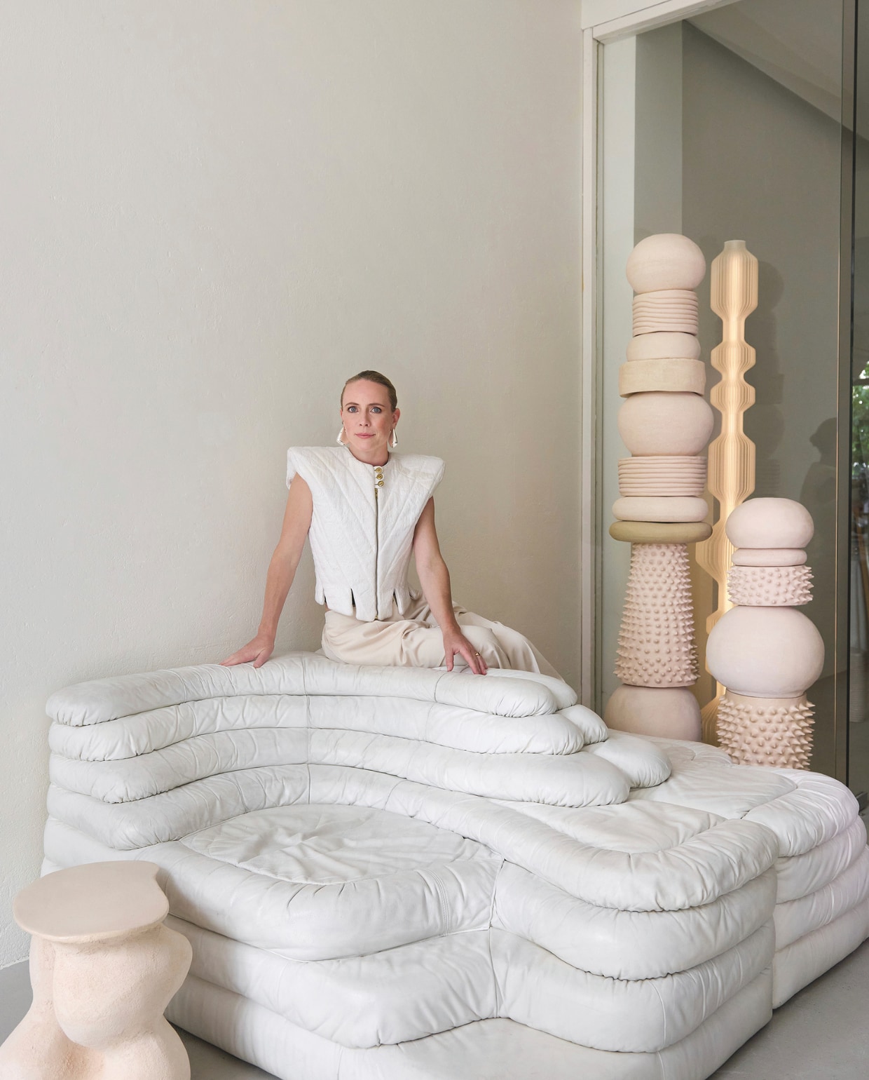 Bank Terrazza van De Sede via Objekt Vintage. Sculpturen 2222Studio. Lamp Lucas Zito. Gloria draagt een top van Tess van Zalinge. Broek Acne Studios. Schoenen Iro. Oorbellen Bottega Veneta. Stijlvol Wonen 9-2025 | styling Marianne Luning | fotografie Kasia Gatkowska | tekst Anneleen Peeters | modestyling Tamara Botter | Visagie Victoria Osborn
