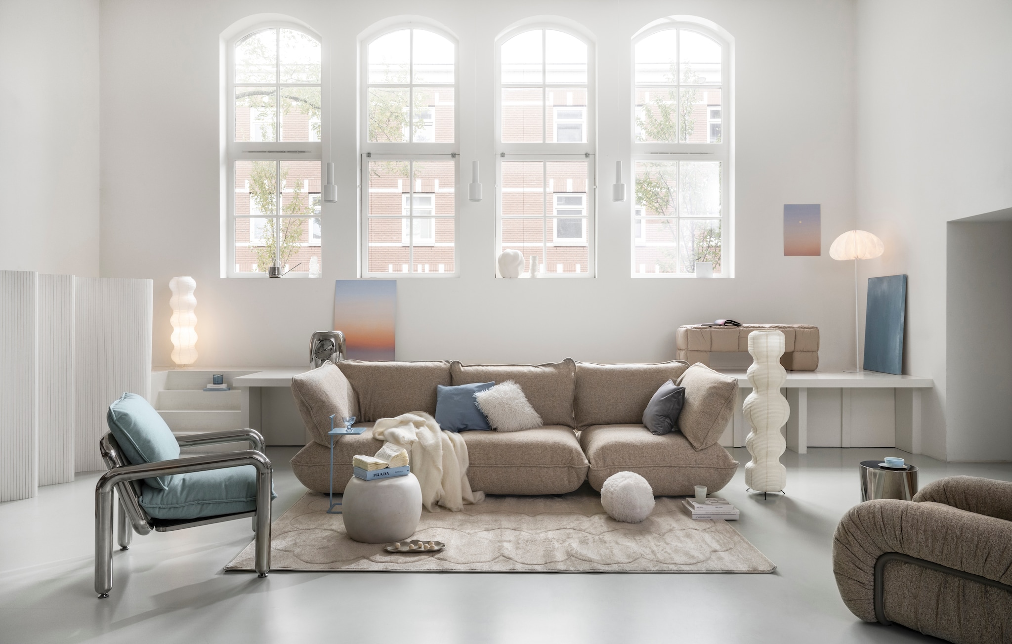 Fatboy bank Sumo, bouclé, beige, 301x108x90 cm (lxbxh) € 3999,-, vloerkleed Bubble Carpet, stof, vanilla ice, 290x200 cm (lxb) € 499,- (fatboy.com). HKliving loungestoel Arc, verchroomd staal en polyester, sand, 101x98x74 cm (bxdxh) € 1650,-, HKliving bankje Puffy, stof Pebble, 140x40x45 cm (lxbxh) € 425,-, HKliving fauteuil Chrome, verchroomd staal en canvas, mint, 80x90x88 cm (bxdxh) € 1295,-, HKliving bijzettafel Currents, chroom, 36x45 cm (Øxh) € 159,-, vtwonen bijzettafel Pebble, betonlook, wit, 50x35 cm (Øxh) € 199,-, Woood bijzettafel Toste, metaal, lichtblauw, 35x25x60 cm (bxdxh) € 79,95, Woood vloerlamp Dalia, papier, wit, 50x150 cm (Øxh) € 169,- (shop.vtwonen.nl). HKliving schaaltje Patio, pale blue € 16,95 (hkliving.com). H&m Home kussenhoes, fluweel, lichtgrijs € 9,99, kussenhoes, linnenmix, dusty blauw € 9,99, vloerlamp rijstpapier, wit, 30x104 cm (Øxh) € 69,99, vloerlamp, rijstpapier, lichtbeige, 30x122 cm (Øxh) € 79,99, grote schaal, terracotta, wit € 39,99, dessertglas, gekleurd glas, blauw € 5,99 (hm.com). Zara Home bijzettafel, roestvrij staal, zilver€ 159,-, koffietafelboek Prada Catwalk € 59,99, deken, wol, ecru, 190x140 cm (lxb) € 149,-, tandenborstelhouder, glas mat, transparant, € 9,99, geurkaars Vibrant Rose, blush grey, 400 g € 22,99 (zarahome.com). Kwantum kussen Bal, polyester, beige € 3,50, kussen Belfort, polyester, wit € 5,-, vaas Melted, keramiek, beige € 19,- (kwantum.nl). Huismerken kamerscherm, bamboe, wit, 400x165 cm (bxh) € 105,- (huismerken.nl). Overig privébezit. vtwonen 01-2026 | styling Sanne Ketelaar | fotografie Stan Koolen