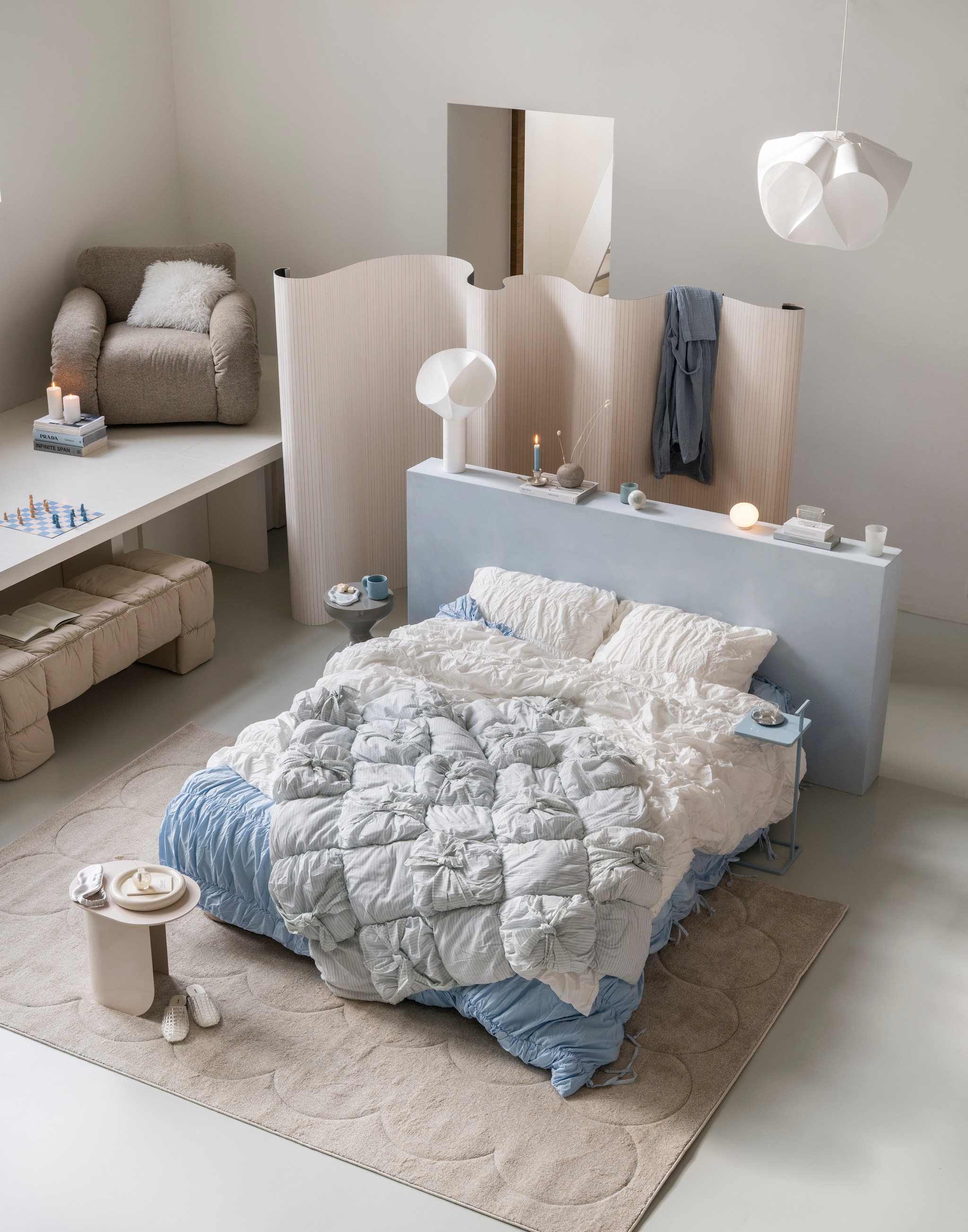 Fatboy vloerkleed Bubble, stof, vanilla ice, 290x200 cm (lxb) € 499,- (fatboy.com). HKliving bankje Puffy, stof Pebble, 140x40x45 cm (lxbxh) € 425,-, HKliving Loungestoel Arc, verchroomd staal en polyester, sand, 101x98x74 cm (bxdxh) € 1650,-,  Woood bijzettafel Floyd, metaal, lichtgrijs, 30x30x47 cm (bxdxh) € 99,95, Woood bijzettafel Toste, metaal, lichtblauw, 35x25x60 cm (bxdxh) € 79,95, Printworks schaakbord Play, lichtblauw € 35,-, (shop.vtwonen.nl). Fést bijzettafel Plateau, hout, zand, 45x45x40 cm (bxdxh) € 289,- (festamsterdam.com). Urban outfitters dekbedovertrekset Marshmallow Puff, katoen, wit, vanaf € 99,-, dekbedovertrekset Cinched, katoen, lichtblauw, vanaf € 99,-, plaid Kai Knotted Puff, katoen, lichtgrijs € 125,- (urbanoutfitters.com). vtwonen muurverf op de lambrisering, ice, 1 liter € 27,99 (karwei.nl). Nordal mok Jose, blauw € 18,94 (nordal.com). H&m Home ochtendjas mousseline, katoen, lichtblauw, maat S/M € 29,99, vaasje, glas, lichtgeel € 4,99 (hm.com). Zara home koffietafelboek Prada catwalk € 59,99, tandenborstelhouder, glas mat, transparant, € 9,99, slippers Jelly open, wit, maat 36 € 29,99, oogmasker, moerbeizijde, grijs, € 22,99, kandelaar, keramiek, zilver, € 25,99, opbergpot borosilicaatglas met letters, transparant € 9,99, mok en schotel, borosilicaatglas, transparant € 11,99 (zarahome.com). Kwantum kussen Belfort, wit € 7,50, schaal Bumper Retro, keramiek, beige € 10,- (kwantum.nl). Flos lamp Glo-Ball Mini, opaalglas, 11x9 cm (Øxh) € 210,- (flos.com). Ikea theelichthouder Vindstilla, glas € 3,99, hanglampkap Bäcknäte, kunststof, wit, 50x36 cm (Øxh) € 29,99, tafellamp Bäcknäte, kunststof, wit, 32x50 cm (Øxh) € 19,99 (ikea.nl). Huismerken kamerscherm, bamboe, wit, 400x165 cm (bxh) € 105,-(huismerken.nl). Søstrene Grene kaars, wit € 1,68 (sostrenegrene.com). vtwonen 01-2026 | styling Sanne Ketelaar | fotografie Stan Koolen