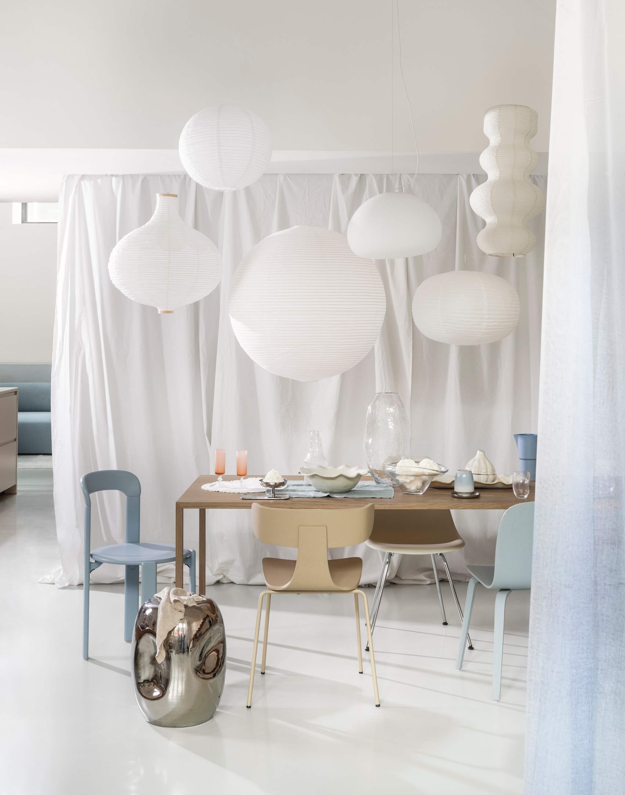 Woood eetkamerstoel Form, hout en metaal, zand, 50x52x79 cm (bxdxh) € 199,-, HKliving bijzettafel Currents, chroom, 36x45 cm (Øxh)€ 159,-(shop.vtwonen.nl). Vitra eetkamerstoel Dsx, kunststof en verchroomd staal, pebble, 46x52x83 cm (bxdxh) € 290,- (vitra.com). Muuto eetkamerstoel Visu, lichtblauw € 349,- (muuto.com). Hay eetkamerstoel Rey, beukenhout, slate blue, 44x49x80 cm (bxdxh) € 579,-, lamp, rijstpapier, wit, 80 cm (Ø) € 65,- (hay.com). Ikea lampenkap Gullsdare, rijstpapier, wit, (Ø) 45 cm € 3,99, lampenkap Risbyn, papier, wit, 57x64 cm (Øxh) € 19,99 (ikea.nl). H&m Home hanglamp, rijstpapier, lichtbeige, 25 cm (Ø) € 69,99, lampenkap, rijstpapier, wit, 65x40 cm (Øxh) € 29,99, grote schaal, terracotta met geschulpte rand, wit € 39,99, karaf, glas € 15,99, glazen, helder glas, set van 2 € 9,99, schaal, asymmetrisch, glas, transparant € 29,99, schaal, ovaal, terracotta, wit€ 49,99 (hm.com). Zara Home servet, katoen, blauw € 39,99 placemat, katoen met ruches, wit € 15,99, opbergpot, knoflookvorm, terracotta, crème € 16,99, (zarahome.com). Arket ijscoupe, roestvrij staal € 22,- (arket.com).  Aquanova beker Figo, aardewerk, Ice € 23,- (bath-living.com). vtwonen 01-2026 | styling Sanne Ketelaar | fotografie Stan Koolen