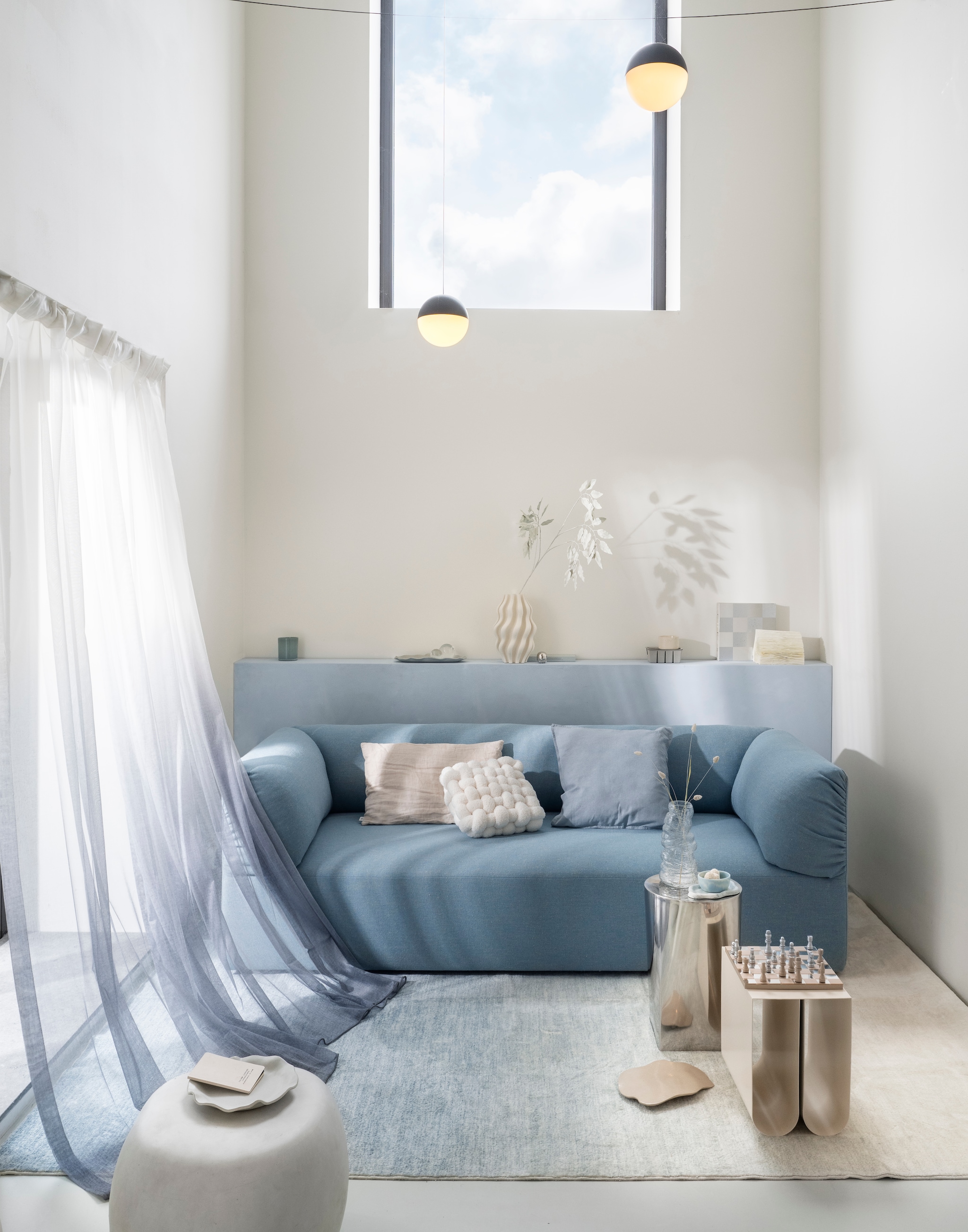 Studio henk driezitsbank Unfold, stof hemp, Dale HWP18, 220x90x70 cm (bxdxh) € 4000,- (studiohenk.nl). Printworks schaakbord Classic art of chess, hout en spiegelglas, zilverkleurig € 125,-, vtwonen bijzettafel Pebble, betonlook, wit, 35x50 cm (Øxh) € 199,-, HKliving schaaltje Patio, pale blue € 16,95,- (shop.vtwonen.nl). H&m home kussenhoes, linnenmix, dusty blauw € 9,99, klein bord met geschulpte rand, terracotta, wit, (Ø) 20 cm € 14,99 (hm.com). Zara home bijzettafel, roestvrij staal, zilver, 30x46 cm (Øxh) € 159,-, rond kistje, metaal, zilver € 6,99, kaars, decoratief keramiek, wit € 15,99 (zarahome.com). Kristina Dam bijzettafel Curved, metaal, beige, 26x35,5x36 cm (bxdxh) € 279,- (kristinadam.dk). Trend carpet gordijn Linda royal, polyester, wit/blauw, 140x260 cm (bxh) € 39,99 (trendcarpet.nl). By mölle kussenhoes, linnen, clay € 59,- (bymolle.com). Karwei vaas, keramiek, wit, 3D-geprint, vtwonen muurverf op de lambrisering, kleur Ice, 1 liter € 27,99,- (karwei.nl). Kwantum vaas Cagnola, glas, transparant € 7,-, kussen Knit, polyester, wit € 25,- (kwantum.nl). Idimex vloerkleed Ombre, wasbaar polyester, lichtblauw met kleurverloop, 200x300 cm (lxb) € 129,- (idimex.de). Ikea kaarshouder Vindstilla, aardewerk, licht grijsgroen € 5,09 (ikea.nl). Stonecloud dienblad, aardewerk, beige, prijs op aanvraag (stonecloudbynika.com). Overig privébezit. vtwonen 01-2026 | styling Sanne Ketelaar | fotografie Stan Koolen