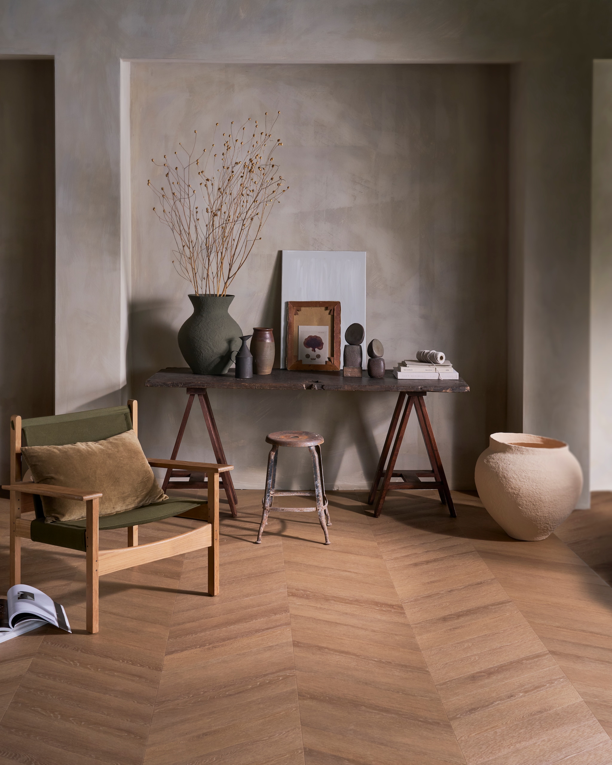 vtwonen pvc-vloer Noble, sunkissed, 53,8x11,7 cm (lxb), dryback, per m² € 48,95.M.m.v. hkliving.com (kussen, fauteuil), urbannatureculture.com (groene vaas, beige pot), marjokedeheer.com (keramieken objecten), nelpunt.nl (houten doosje), pietjonker.nl (tafel, kruk, zwarte kan, bruine pot). Overig privébezit. vtwonen Landelijk 01-2026 | styling Cleo Scheulderman | fotografie Jeroen van der Spek