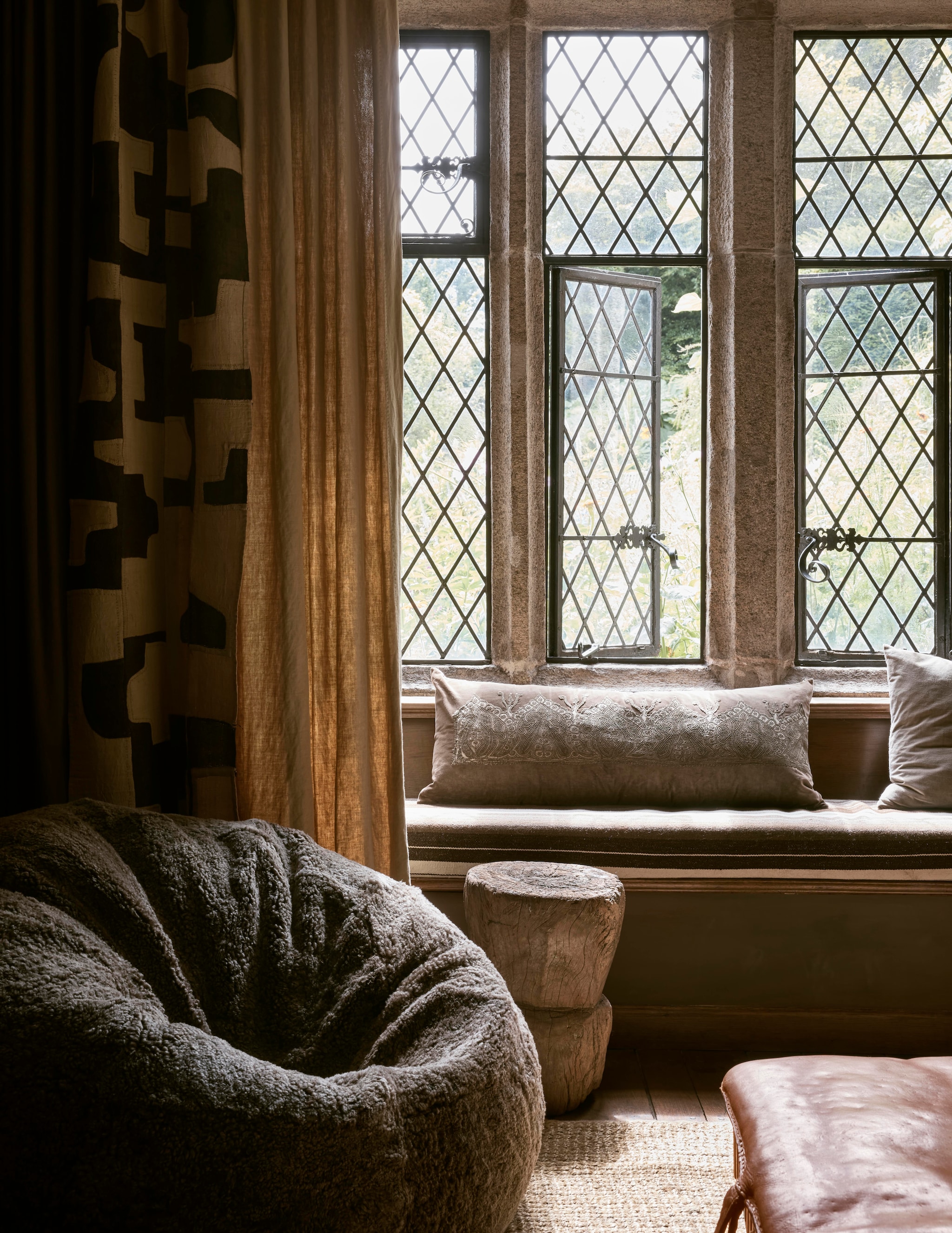 Gordijnen van vintage handgeverfde linnen lakens uit Hongarije en Afrikaans kubadoek, kussens van Turkse kleden en antieke stoffen door Retrouvius Antique. Zitzak schapenvacht The Wool Company. Leren turnbank vintage. Muurkleur Aubergine van Bauwerk. vtwonen Landelijk 12-2025 | styling Retrouvius | fotografie Martin Morrell