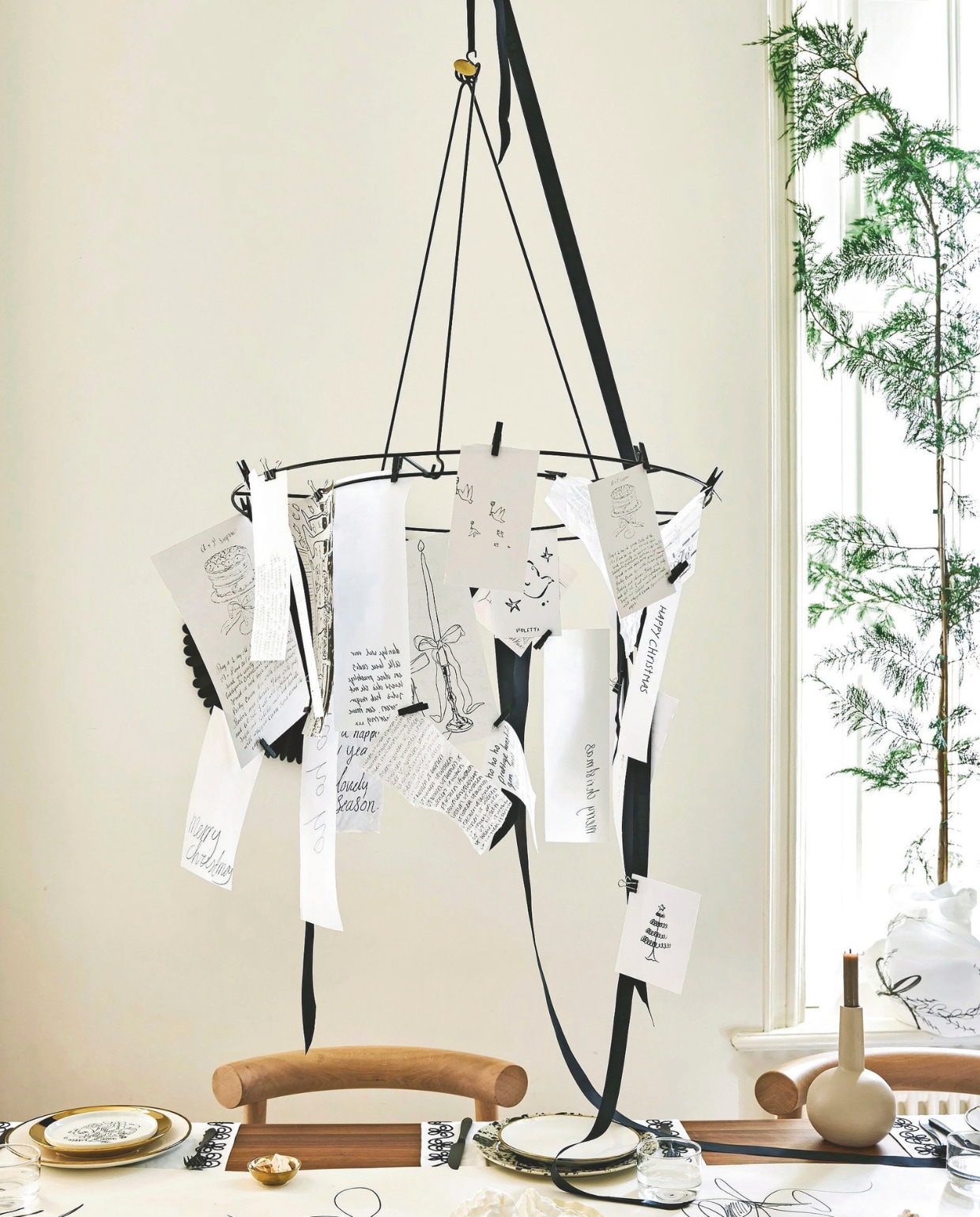 vtwonen decoratiering, metaal, zwart en goud, 60 cm (Ø) € 29,95, vtwonen borden, porselein, wit-goud, 25,5 cm (Ø) set van 2 € 25,-, vtwonen petitfourborden, porselein, goud, 12 cm (Ø), set van 4 € 24,95, vtwonen kandelaar, metaal, flax, 17x22 cm (Øxh) € 16,95, vtwonen bestekset, staal, matzwart, 18-delig € 89,- en vtwonen schaaltjes, porselein, goud, 7 cm (Ø), set van 4 € 14,95.M.m.v. studio-henk.nl (stoel, tafel), arket.com (tafelloper, geïllustreerd bord). Overig privébezit. vtwonen 11-2025 | styling Sanne Ketelaar | fotografie Stan Koolen