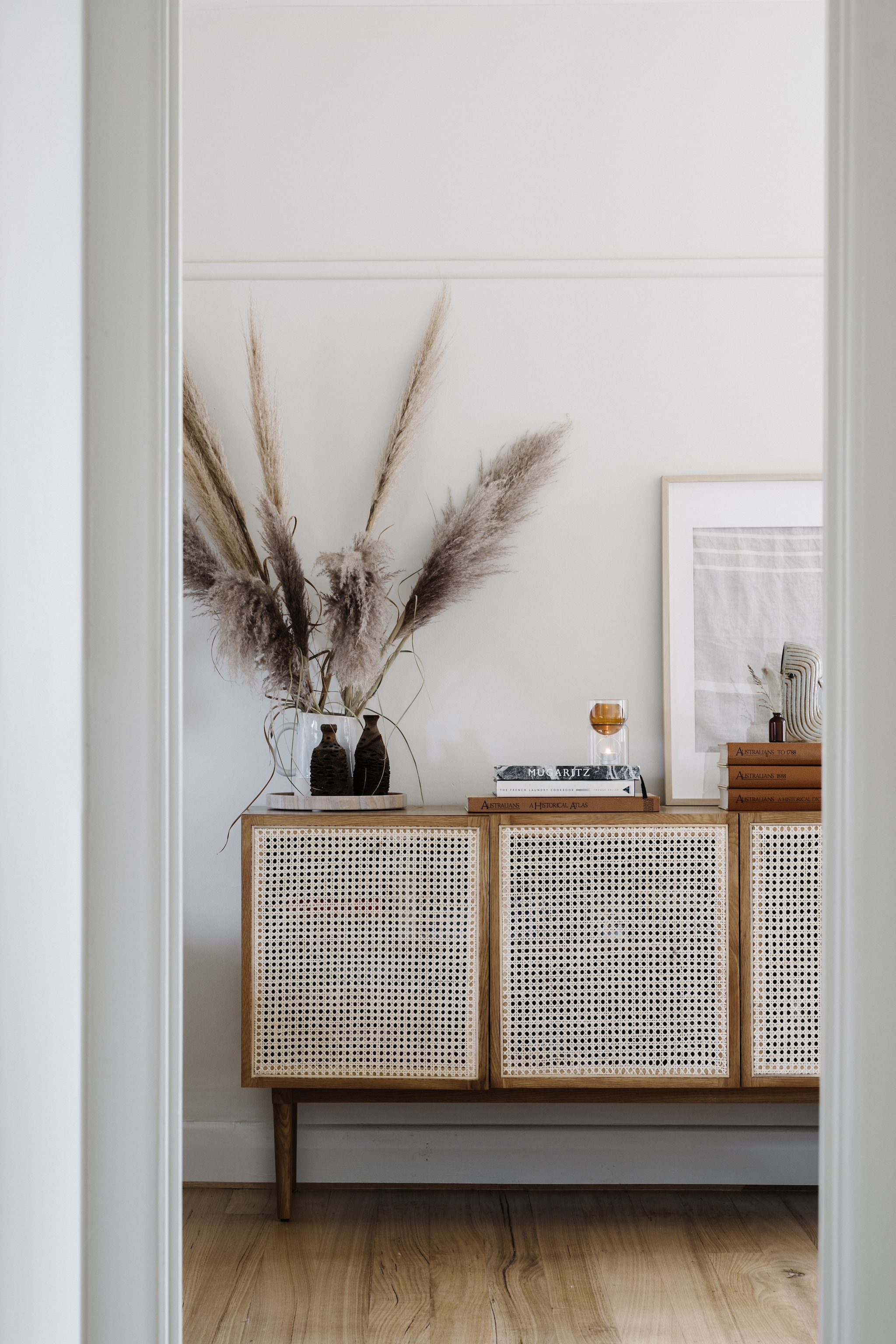 Rotan dressoir Lounge Lovers. Kunstwerk gemaakt door Gemma. Boeken Royal Historical Society of Australia. vtwonen Landelijk 02-2026 | fotografie Marnie Hawson | productie Living Inside