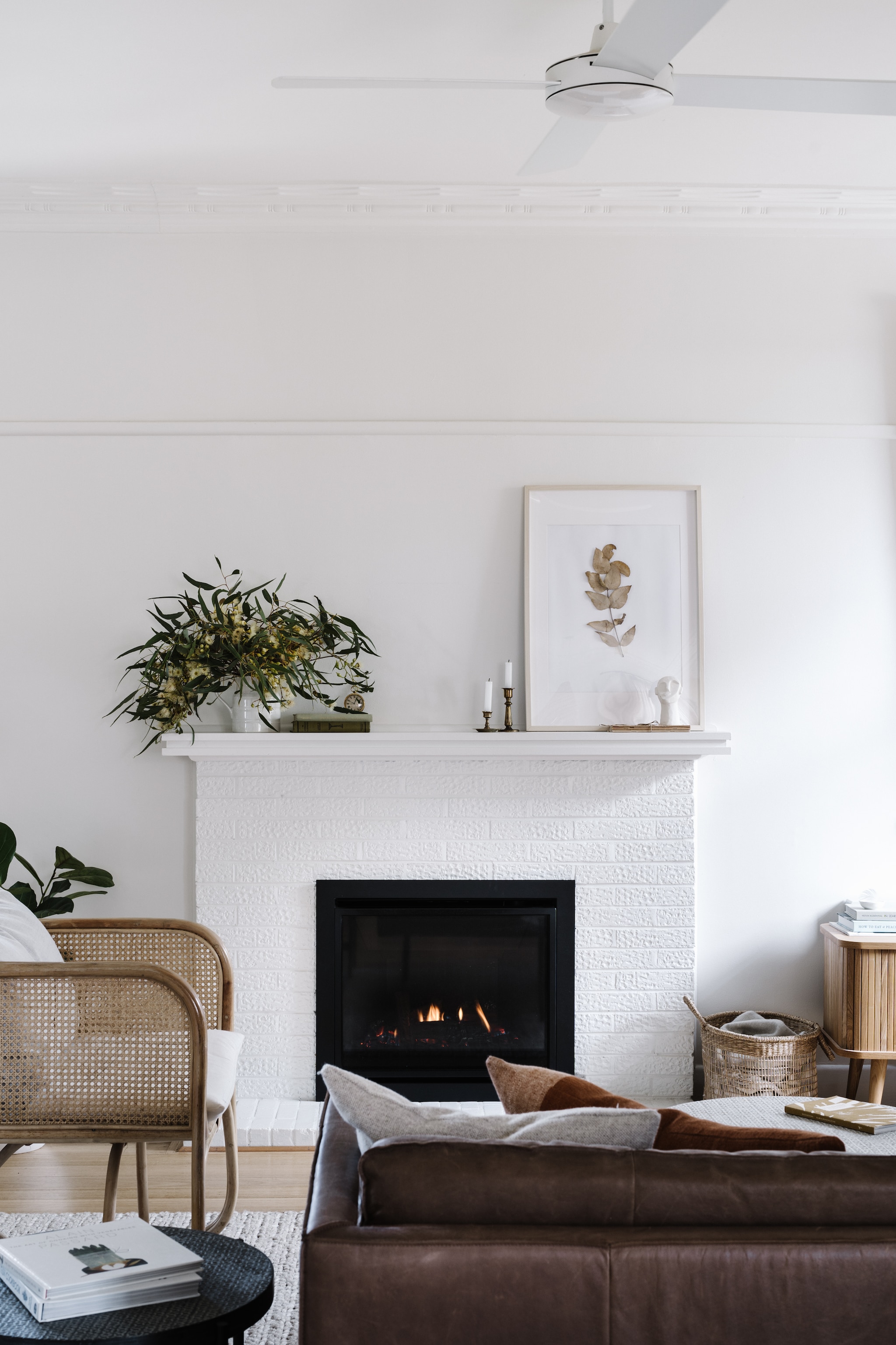 Eucalyptus is een van Gemma’s favoriete planten om te laten zien. Het kunstwerk maakte ze zelf door een tak te drogen. Bank Lounge Lovers. Stoel Bunnings. Kandelaars vintage. vtwonen Landelijk 02-2026 | fotografie Marnie Hawson | productie Living Inside