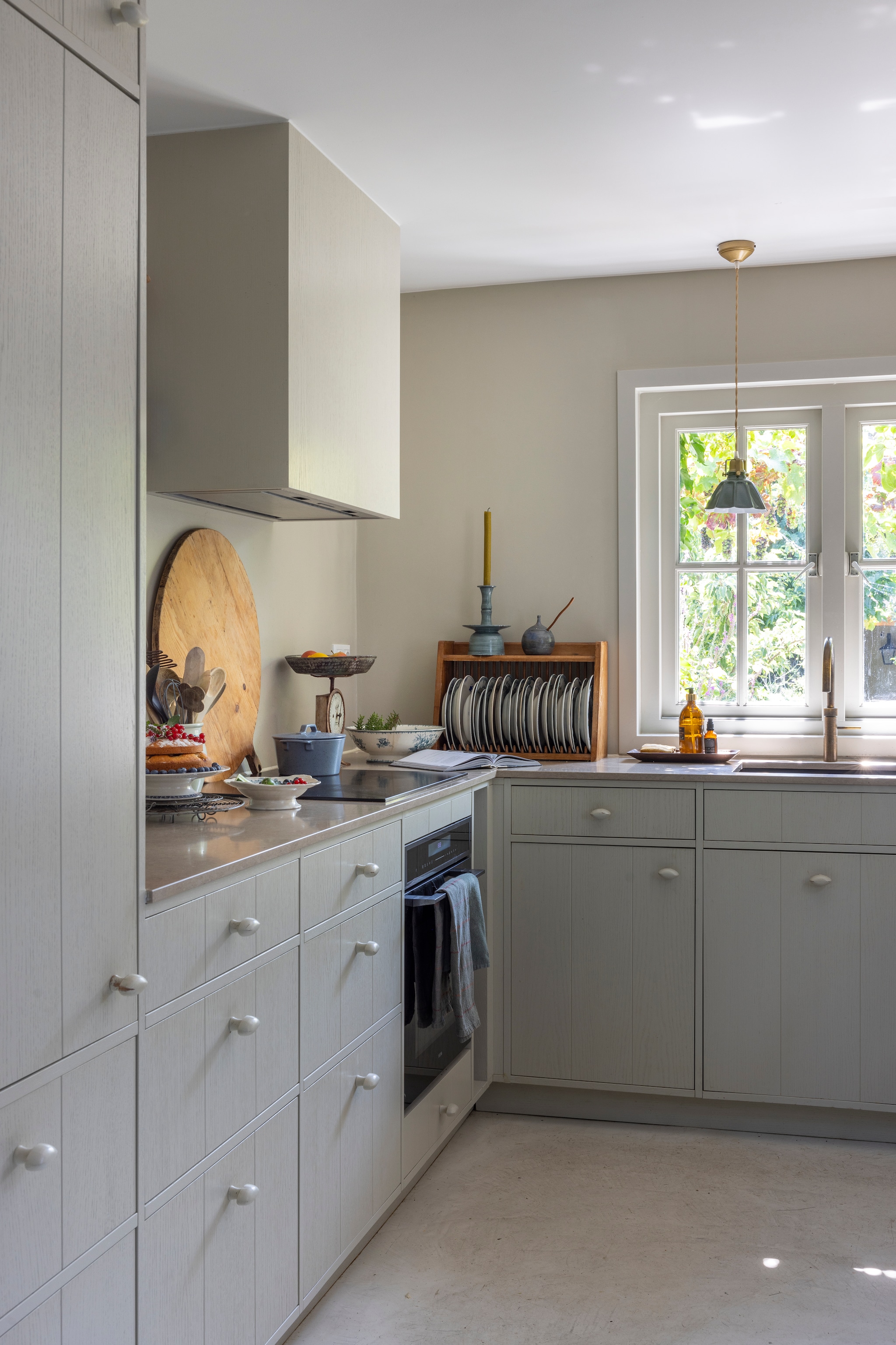 Keukenontwerp Zv Wonen, uitgevoerd door de zoon van Jayne en Jan. Kleur keuken Schelp van l’Authentique. Bronzen kraan Quooker. Bordenrek tweedehands uit Zweden. Kandelaar vtwonen. Potje souvenir uit Zweden. Zeepflacons Zv Wonen. Weegschaal veiling Haarlem. Schalen Zweeds antiek. Braadpan Broste Copenhagen. Houten plateau Oldwood. Onderzetter Bloomingville. Theedoek Greengate. Lamp Atelier Swoop. vtwonen Landelijk 02-2026 | fotografie Anneke Gambon