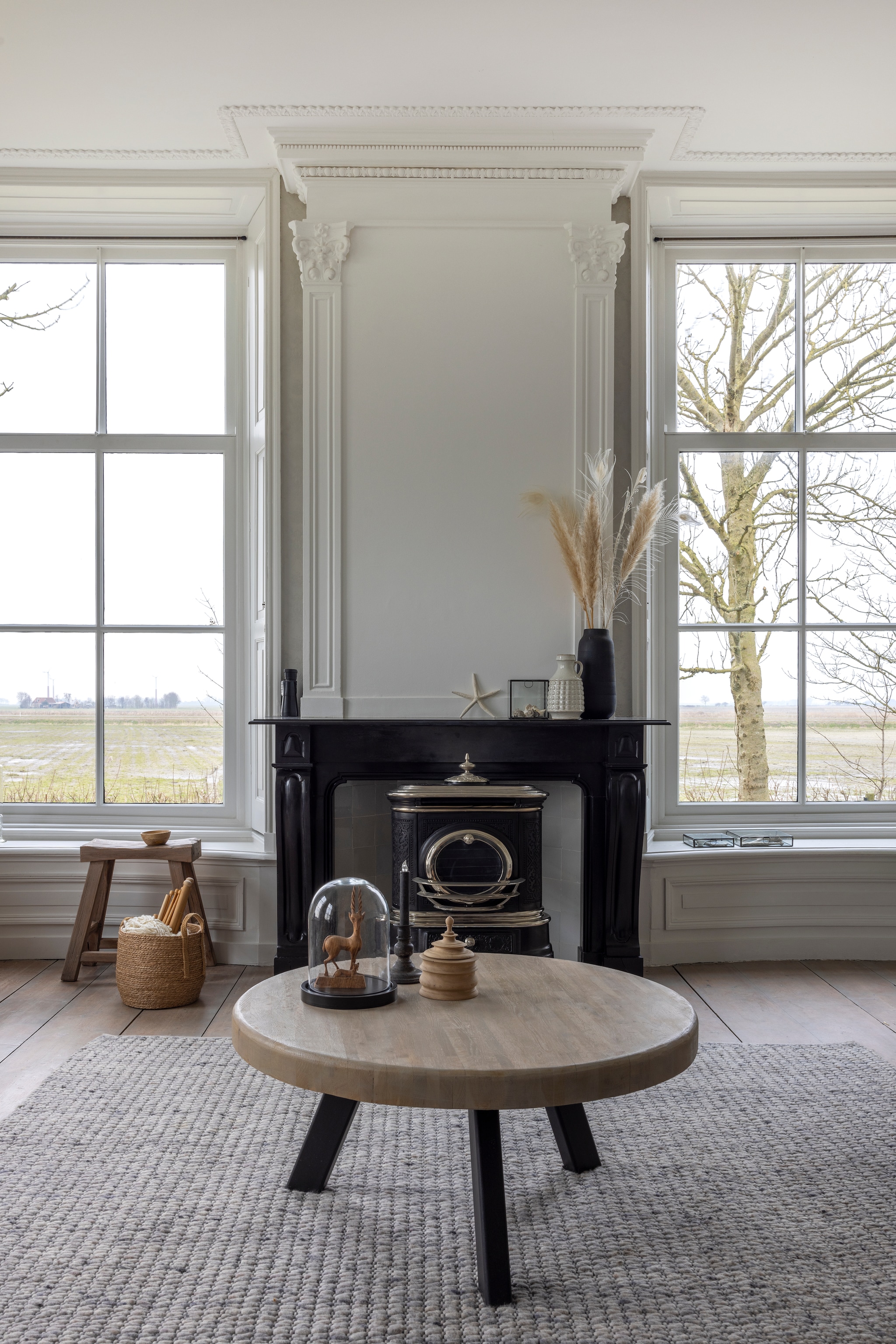 Blad salontafel kringloop, geschuurd en gebeitst door Loesanne. Onderstel gemaakt door Tsjebbe. Schouw origineel. Kachel zat in het voorhuis. Rieten mand Karwei. Breipennen WenKR8. vtwonen Landelijk 02-2026 | fotografie Anneke Gambon