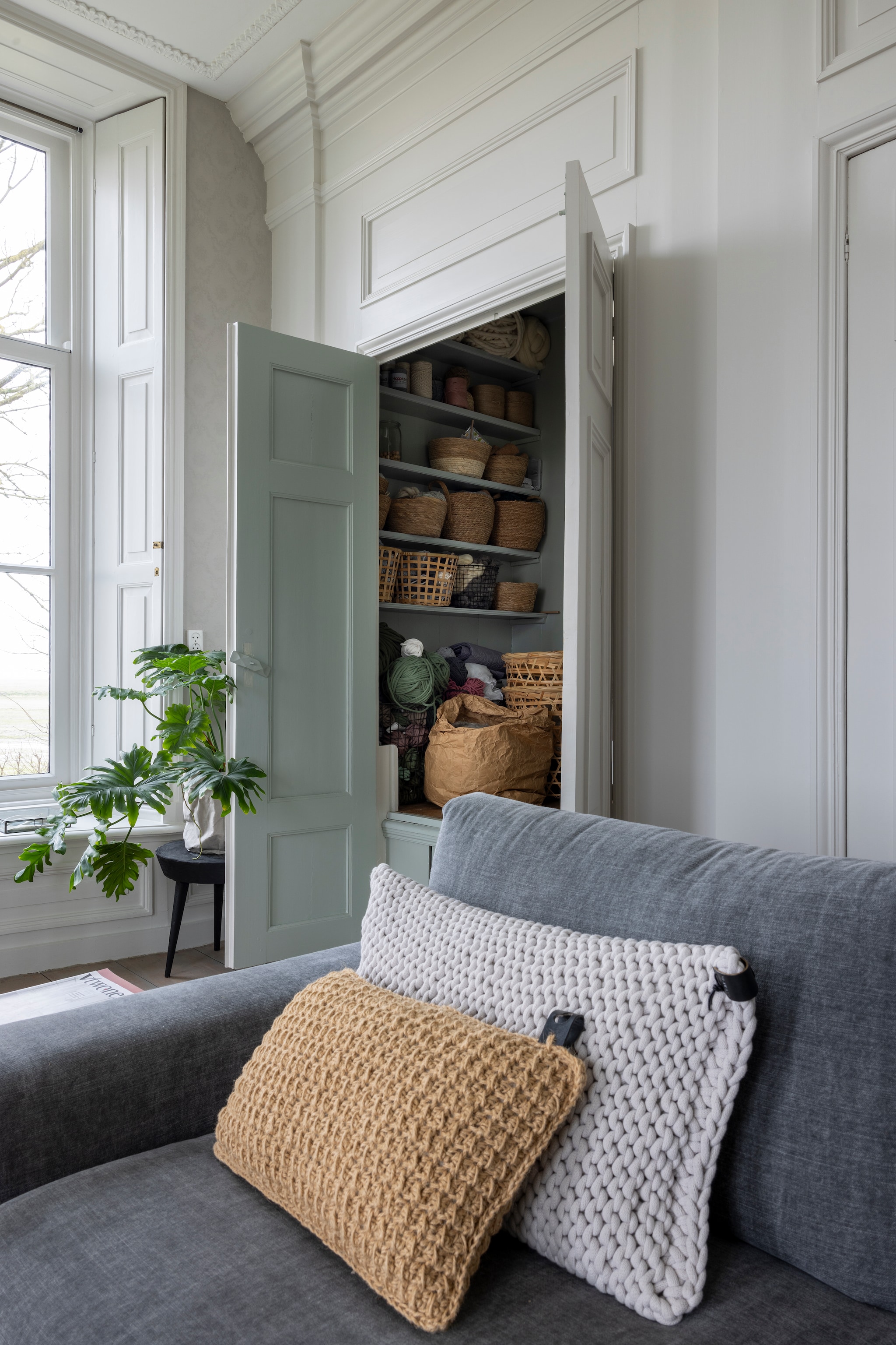 Kussens WenKR8. In de bedsteewand bewaart Loesanne in rieten manden haar mooiste wol. Grote manden Karwei, Ikea, kleine manden Action. vtwonen Landelijk 02-2026 | Fotografie Anneke Gambon