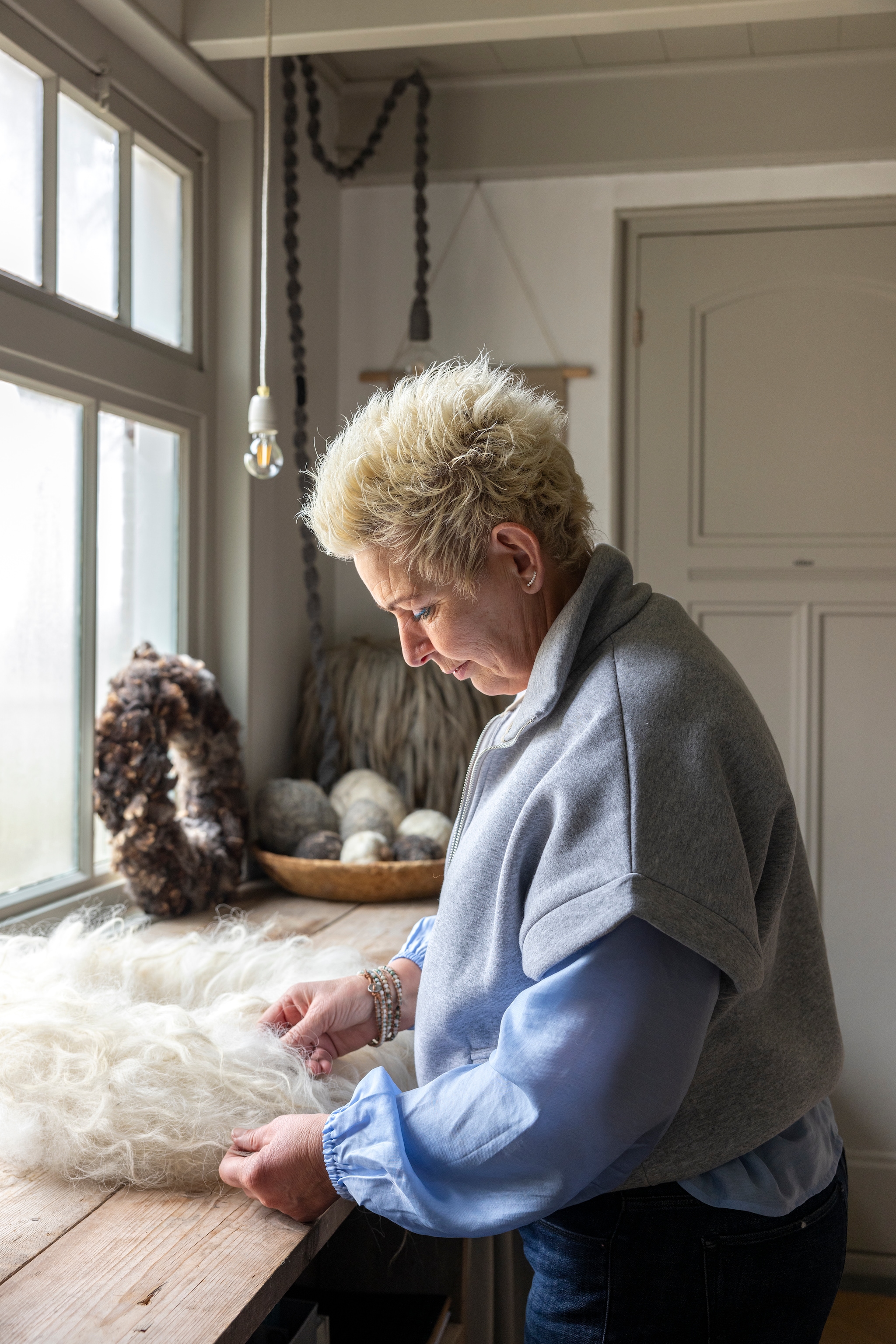Loesanne in haar wolatelier. Plafondlamp met wolkoord en krans WenKR8. vtwonen Landelijk 02-2026 | fotografie Anneke Gambon