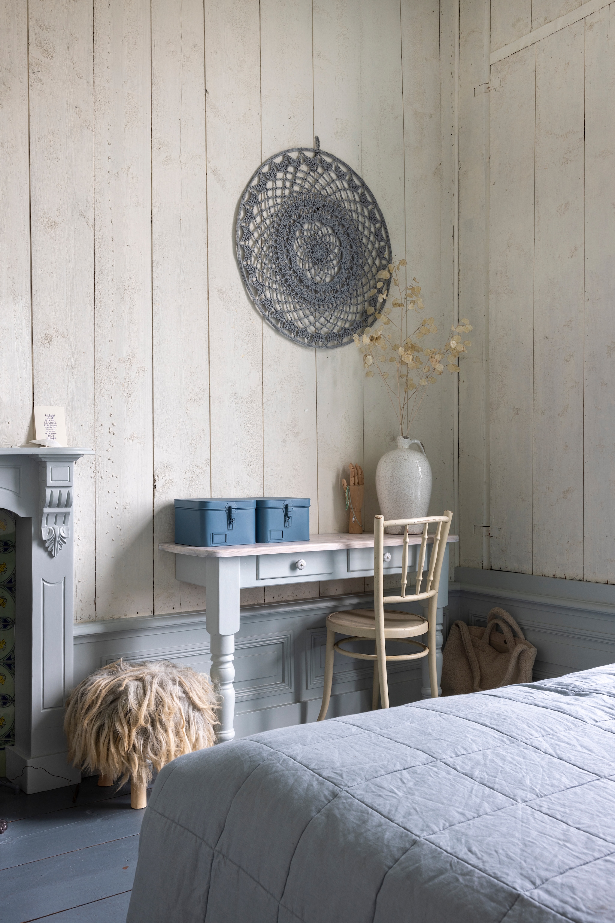 Gehaakte wanddecoratie WenKR8. Schrijftafel Marktplaats, doormidden gezaagd en geverfd. Stoel erfstuk. Poef Action. Vacht erop WenKR8. Schouw origineel. Kleur schouw Dawn en kleur wand Cotton White van Painting the Past. vtwonen Landelijk 02-2026 | Fotografie Anneke Gambon
