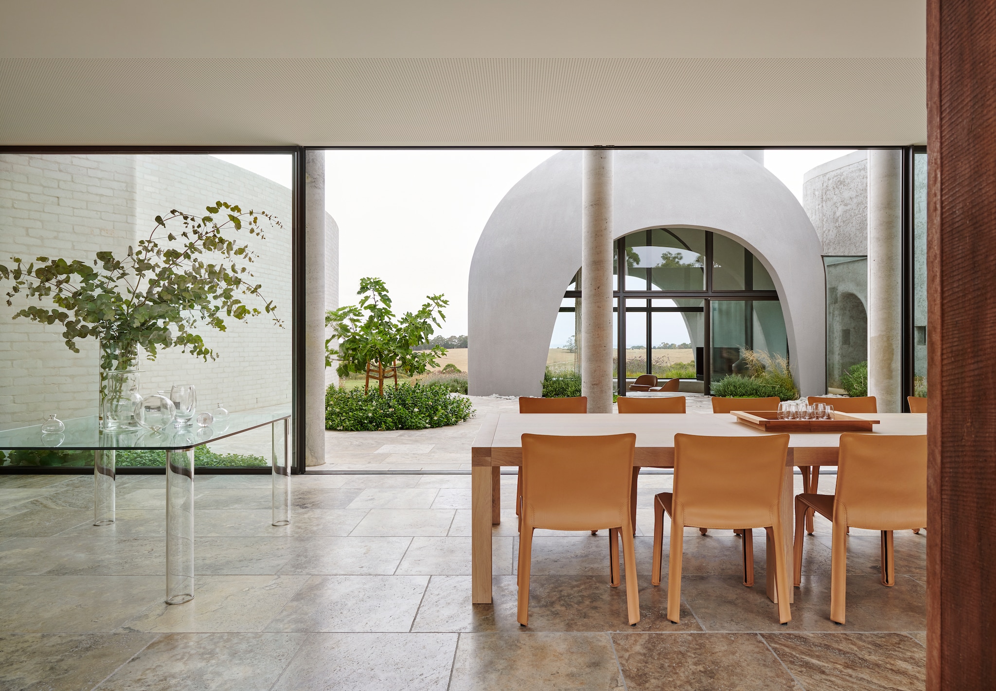 Glazen tafel Glas Italia. Eettafel van massief eiken Motto Furniture & Cabinetry. Stoelen Cab van Mario Bellini. vtwonen Design 01-2026 | productie Living Inside | fotografie Lisa Cohen