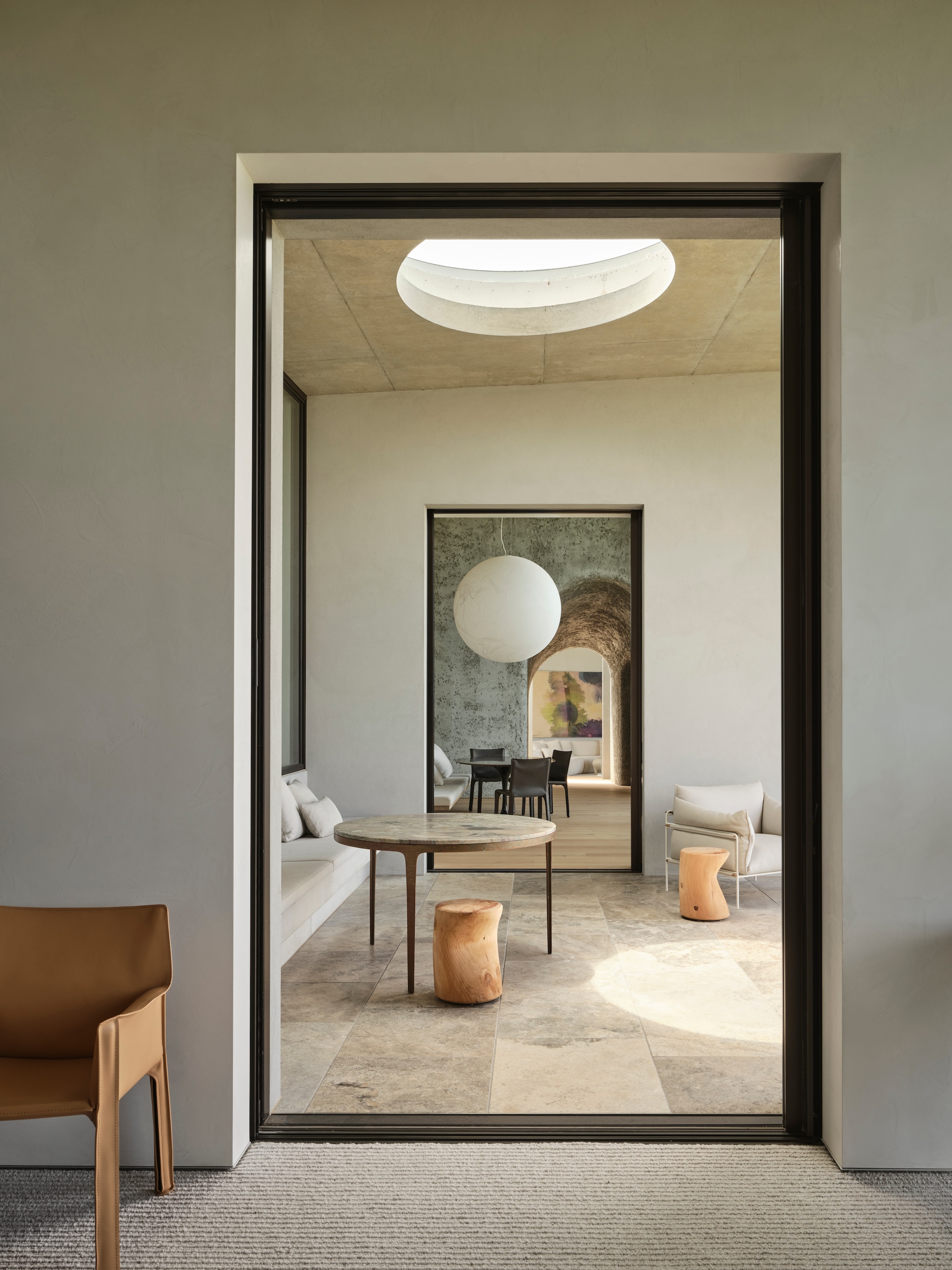 Stoel Cab binnen Mario Bellini. Bronzen tafel Barbera Design. Krukken Riva 1920. Fauteuil Paola Lenti. Op maat gemaakte bank in overdekte buitenlounge. vtwonen Design 01-2026 | productie Living Inside | fotografie Lisa Cohen