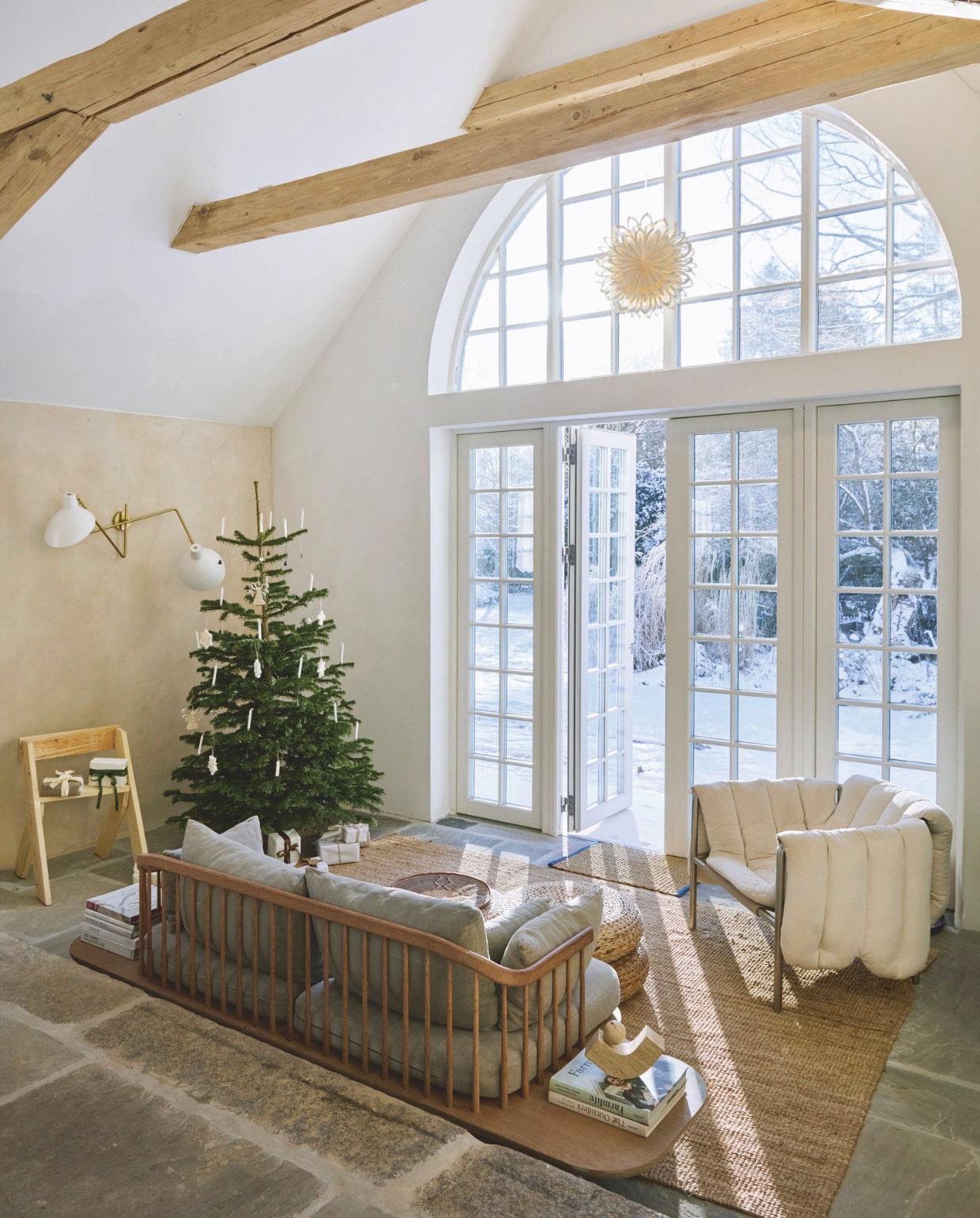 Kruk zelfgemaakt door zoon Charley. Cadeaupapier en lint Self Made. Wandlamp Astep. Bank Fly van Space Copenhagen. Bijzettafel en poef &Tradition. Marmeren boekensteun Caché. Loungestoel ontworpen door Faye Toogood voor Hem. Ster voor het raam Sara Du Nord. Boom versierd met origamisterren en echte kaarsen in houders. vtwonen 11-2025 | fotografie glottipress