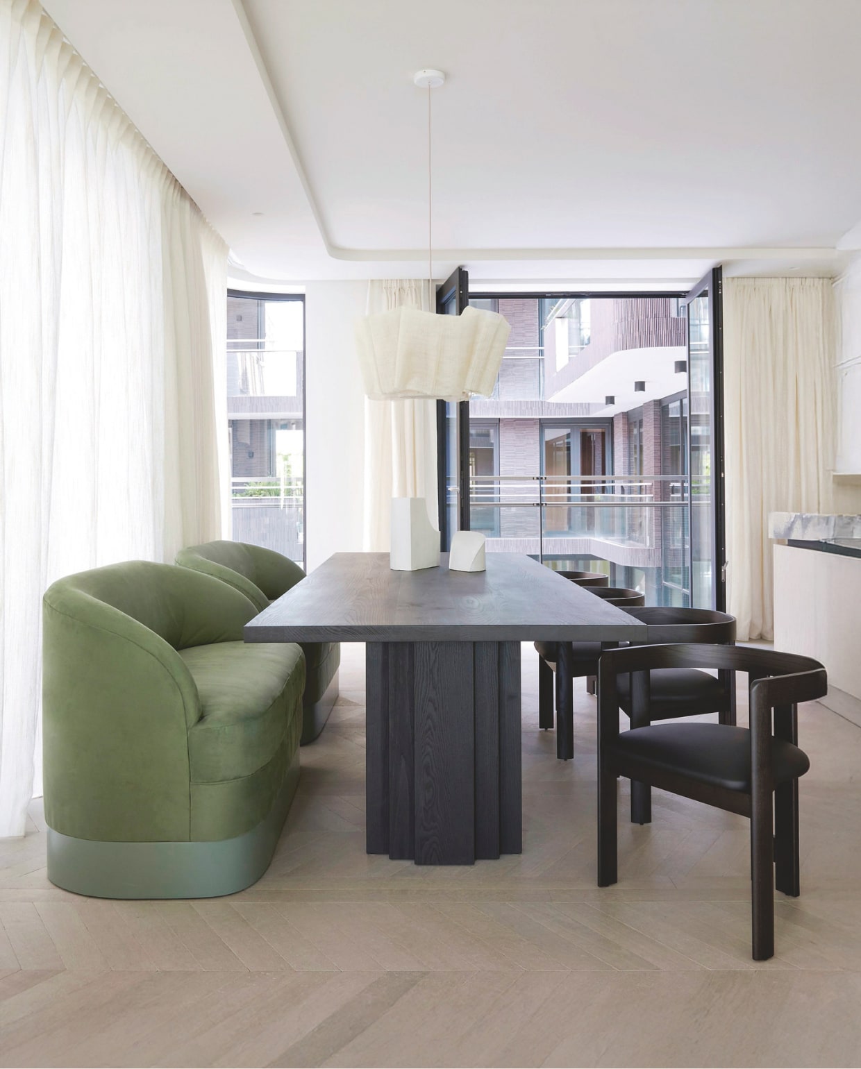 Banken op maat ontworpen door Framework Studio in imitatiesuède. Tafel Mokko Amsterdam. Hanglamp Pinch. Stoelen Pigreco, heruitgave door Tacchini Italia. Keramieken sculpturen Emidio Galassi. Vloer Frans eikenhout op maat gemaakt patroon van Framework Studio. Stijlvol wonen 9-2025 | fotografie Kasia Gatkowska