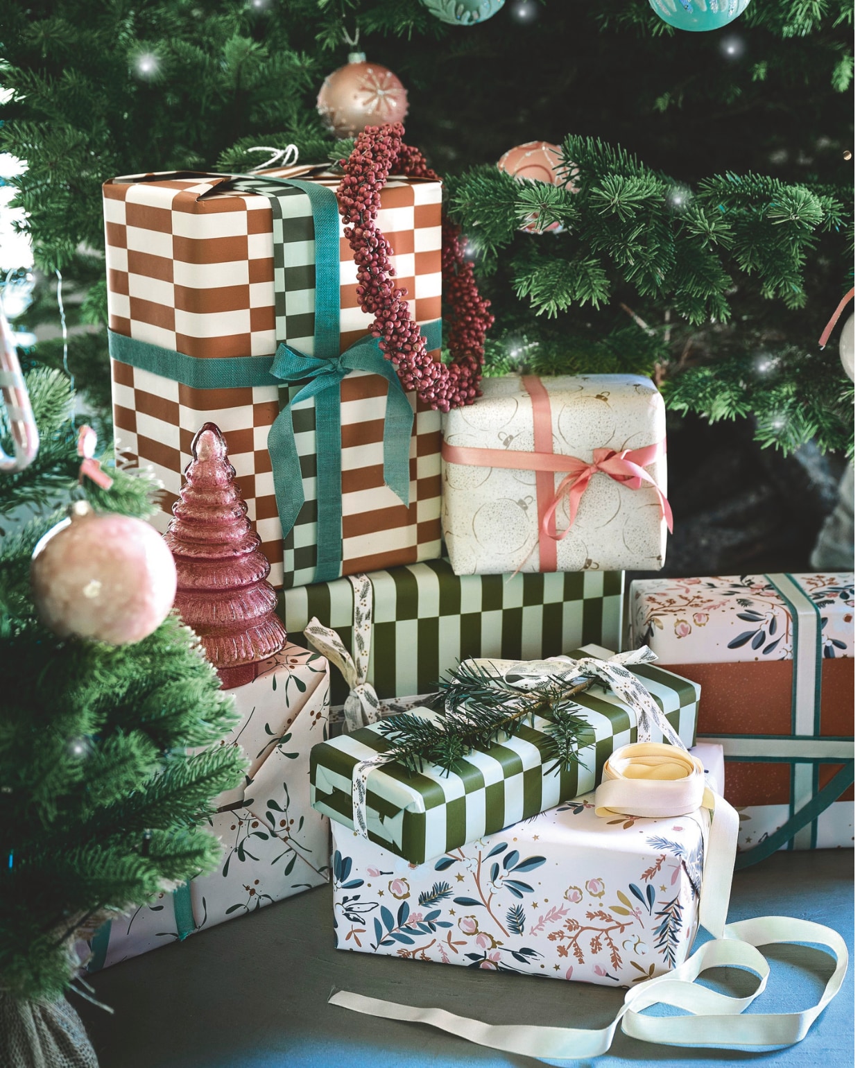 Buitengoed De Boomgaard grote kerstboom (buitengoeddeboomgaard.nl). Weldaad krans, messing en hout, oudroze, 24 cm (Ø) € 39,95, decoratie kerstboom, handgemaakt, glas, roze € 17,95 (weldaad.com). Edith Beurskens kerstballen, keramiek, roze, 6 cm (Ø) € 45,-, 8 cm (Ø) € 50,- (edithbeurskens.com). Dagmara kerstbal met details, glas, pastelroze, set van 4 € 23,90, kerstornament zuurstok Candy Cane, glas, roze, set van 2 € 15,90 (shop.vtwonen.nl). Collectivwarehouse cadeaupapier Comfort & Joy, papier, 300x50 cm (lxb), set van 5 rollen€ 7,95, lint, satijn, lichtroze € 2,99, sierlint Mistletoe, katoen, offwhite en grijs-goud, 2000 cm (l) € 9,59 (collectivwarehouse.com). vtwonen kerstspecial | styling Liza Wassenaar | fotografie Sjoerd Eickmans