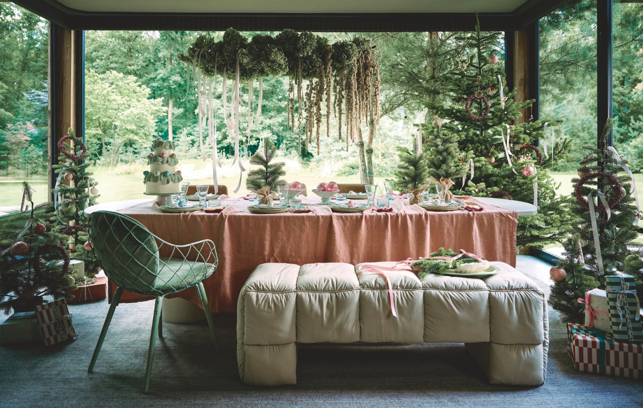 Pebb. eettafel, betonlook, shade of linen, 300x110 cm (lxb) € 2400,- (pebb.nl). Buitengoed De Boomgaard grote kerstboom (buitengoeddeboomgaard.nl). Edelman kerstboom Nagoya, 25x45 cm (bxh), prijs op aanvraag, kerstboom middelgroot, 60x90 cm (bxh), prijs op aanvraag, kerstverlichting, warm, 50 ledlampjes, 500 cm (l), prijs op aanvraag (edelman.eu). HKliving bank Puffy Lobby, mdf en katoen, pebble, 140x40x45 cm (lxbxh) € 425,-, schaal, epoxy giethars, ivoor € 54,95, geribbelde schalen, steen, mintgroen € 39,95, schaal, keramiek, mint-terracotta € 59,95, taartplateau, steen, saliegroen € 59,95, kaasmessen saliegroen, polyresin, set van 3 € 29,95, kaasmessen citroengeel, polyresin, bolletjes, set van 3 € 29,95, kaasmessen roomkleur, polyresin, set van 3 € 32,95, borden, keramiek, mosgroen, vanaf € 14,- (hkliving.com). H&m Home tafelkleed, linnenmix, roze € 49,99, servetten, linnenmix, rood, set van 4 € 14,99, gestreepte borden, porselein, lichtturkoois € 7,99 (hm.com). Household Hardware glazen Kadousse, medium, gerecycled glas € 5,95, wijnglazen Diabolo, medium, gerecycled glas € 7,50 (householdhardware.nl). Collectivwarehouse lint, satijn, lichtroze, 2500 cm (l) € 2,99, sierlint Mistletoe, katoen, offwhite en grijs-goud, 2000 cm (l)€ 9,59, cadeaupapier Comfort & Joy, papier, 300x50 cm (lxb), set van 5 rollen € 7,95 (collectivwarehouse.com). Edith Beurskens kerstballen, keramiek, roze, ivoor en mintgroen, 6 cm (Ø) € 45,-, 8 cm (Ø) € 50,- (edithbeurskens.com). Dagmara kerstbal met details My Christmas, glas, pastelroze, set van 4 € 23,90, kerstornament zuurstok Candy Cane, glas, zachtroze, set van 2 € 15,90, kerstbal, glas, mintgroen, set van 4 € 27,90 (shop.vtwonen.nl). Weldaad krans, messing en hout, oudroze, 24 cm (Ø) € 39,95, ornament krans, glas, roze € 9,95 (weldaad.com). Judith Slagter krans en florale styling boven tafel, prijs op aanvraag (judithslagter.nl). Elisabeth & Valentijn traktaties op schaal en taart, pastelkleuren, prijs op aanvraag (elisabethvalentijn.com). Dém Rae strikontwerp op bord, prijs op aanvraag (demrae.com). Drukkerij Flora strikprint op bord, prijs op aanvraag (drukkerij-flora.nl). De Machinekamer stoel voor, vintage, mintgroen, prijs op aanvraag, stoelen achter tafel, gestoffeerd, diverse kleuren, vanaf € 294,- (demachinekamer.nl). vtwonen kerstspecial | styling Liza Wassenaar | fotografie Sjoerd Eickmans