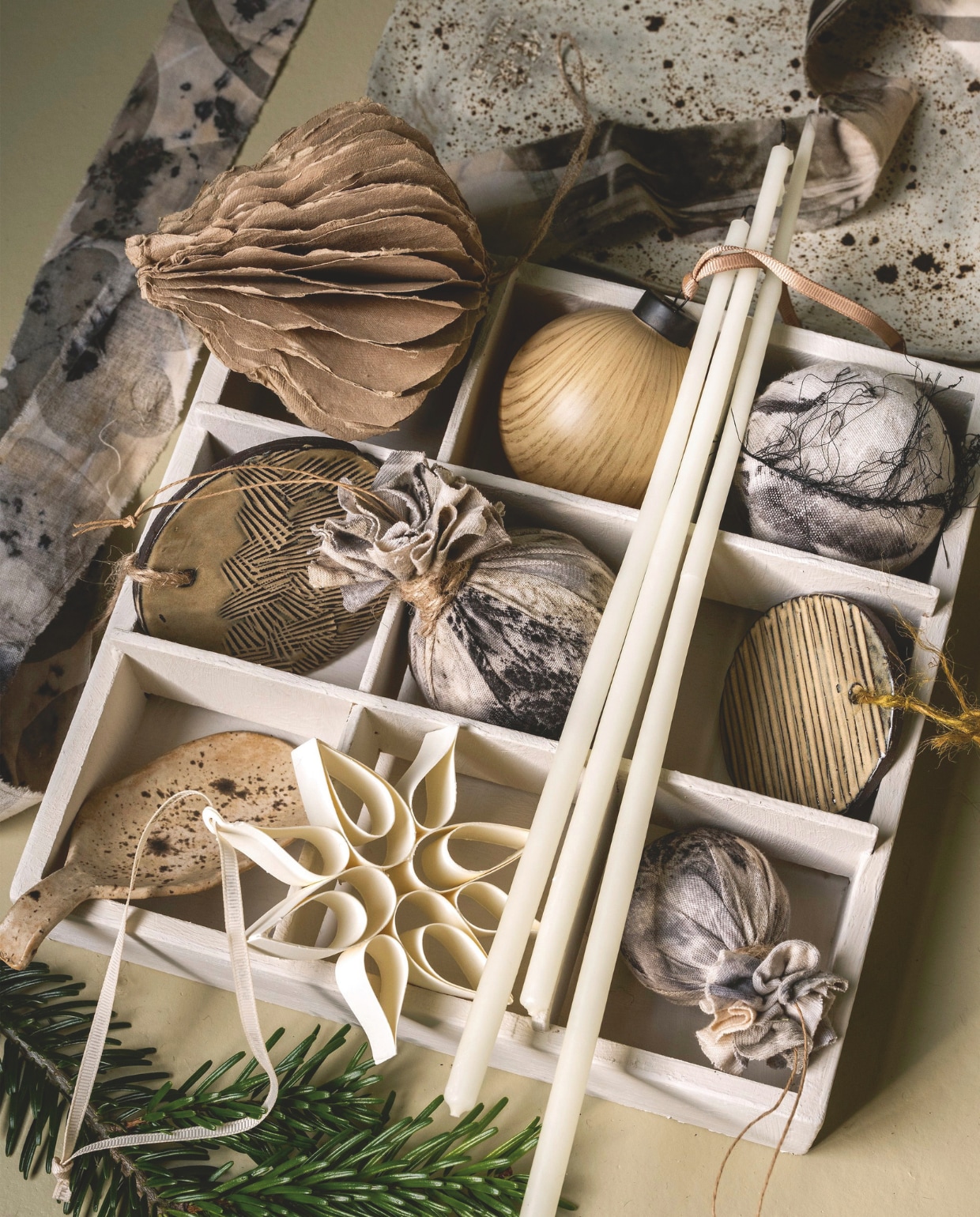 Madam Stoltz Honingraat ornament, gerecycled papier, zand, set van 2 € 15,25 (deens.nl). Blomus kerstbal Kiseky, houtlook, beige, set van 4 € 34,95 ornamenten Kazary, papier, gevouwen, wit, set van 4 € 24,95, (blomus.com). @carolinelovesceramics kerstbal plat, keramiek, naturel, vanaf € 6,-, lepel, keramiek, prijs op aanvraag, plateau, keramiek, naturel € 18,- (@carolinelovesceramics). Amber Maakt kerstballen, textiel, ecoprint, € 17,- en € 25,- (ambermaakt.nl). Decoflorall bloemsteekkaars, wit, 40 cm, set van 12 € 8,99 (decoflorall.nl). vtwonen 11-2025 | styling Marianne Luning | Stan Koolen
