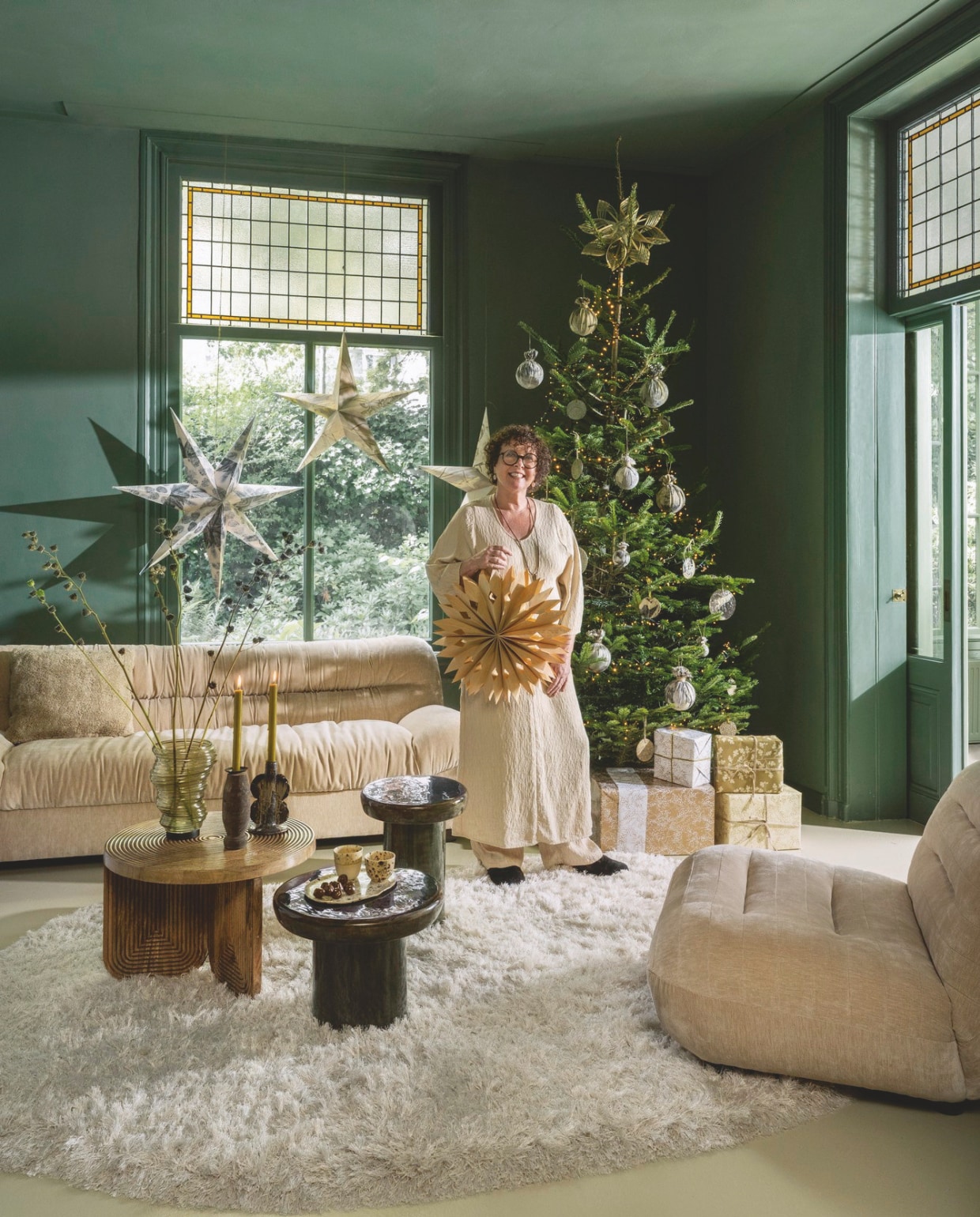 Dutchbone bank Douglas, velours, beige, 214x103x78 cm (lxbxh) € 2595,-, fauteuil Wyatt, velours, beige, 101x87x70,5 cm (lxbxh) € 869,-, bijzettafels Mush, mangohout, groen, 35x45 cm (Øxh) en 45x35 cm (Øxh) € 149,- en 189,-, Sfeer voor jou lichtsnoer, groen, 2 m € 90,-, J-Line vaas Tornado, glas, groen € 40,40, kandelaar Naga, keramiek, bruin € 30,40 (shop.vtwonen.nl). Zuiver vloerkleed Tasty, hoogpolig wolmix, wit, 200x290 cm (lxb) € 765,- (zuiver.com). Housecraft salontafel, mangohout, bruin, 60x40 cm (Øxh) € 299,- (housecraftliving.com). Ompak cadeaupapier (kookwinkel.nl). Ambermaakt kerstballen, textiel, ecoprint, klein€ 17,-, groot € 25,-, kerststerren, papier, ecoprint, naturel, vanaf € 250,- (ambermaakt.nl). @carolinelovesceramics kerstballen plat, keramiek, naturel, vanaf € 6,-, bord, ovaal, keramiek € 20,-, kopjes, keramiek € 14,-(@carolinelovesceramics). Madam Stoltz kandelaar, geüpcycled hout, set van 3 € 24,75 (madamstoltz.nl). Deens kerstster, bamboe € 17,25 (deens.nl). vtwonen 11-2025 | styling Marianne Luning | Stan Koolen
