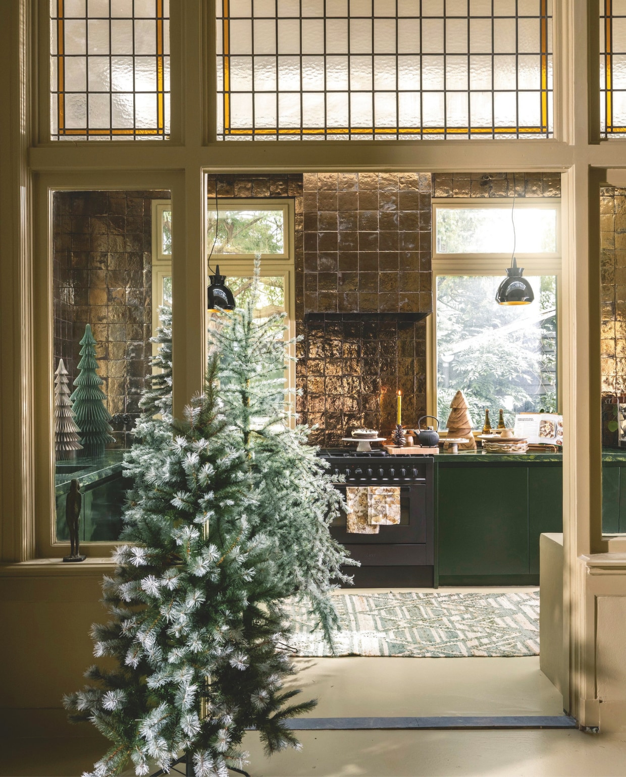 Sfeer voor Jou kerstboom Medford groen-wit, vanaf € 115,- kerstboom Springdale groen-wit, vanaf € 115,-, kerstboom Kingston groen-wit, vanaf € 115,-, vtwonen wandtegels Villa, keramiek, gold metallic, per m² € 108,- (shop.vtwonen.nl). Madam Stoltz kerstbomen, papier, groen, grijs, vanaf € 48,25, kandelaar dennenappel, metaal, bruin € 24,-, kerstboom, hout, bruin € 31,- (deens.nl). Dille & Kamille taartschaal op voet, porselein, wit € 19,95, theepot met onderzetter, gietijzer, zwart € 59,95, theesprankel 0% € 12,95 (dille-kamille.nl). @carolinelovesceramics borden, keramiek € 30,-, taartschaal op voet, keramiek, naturel € 32,- (@carolinelovesceramics). Overig privébezit. vtwonen 11-2025 | styling Marianne Luning | Stan Koolen