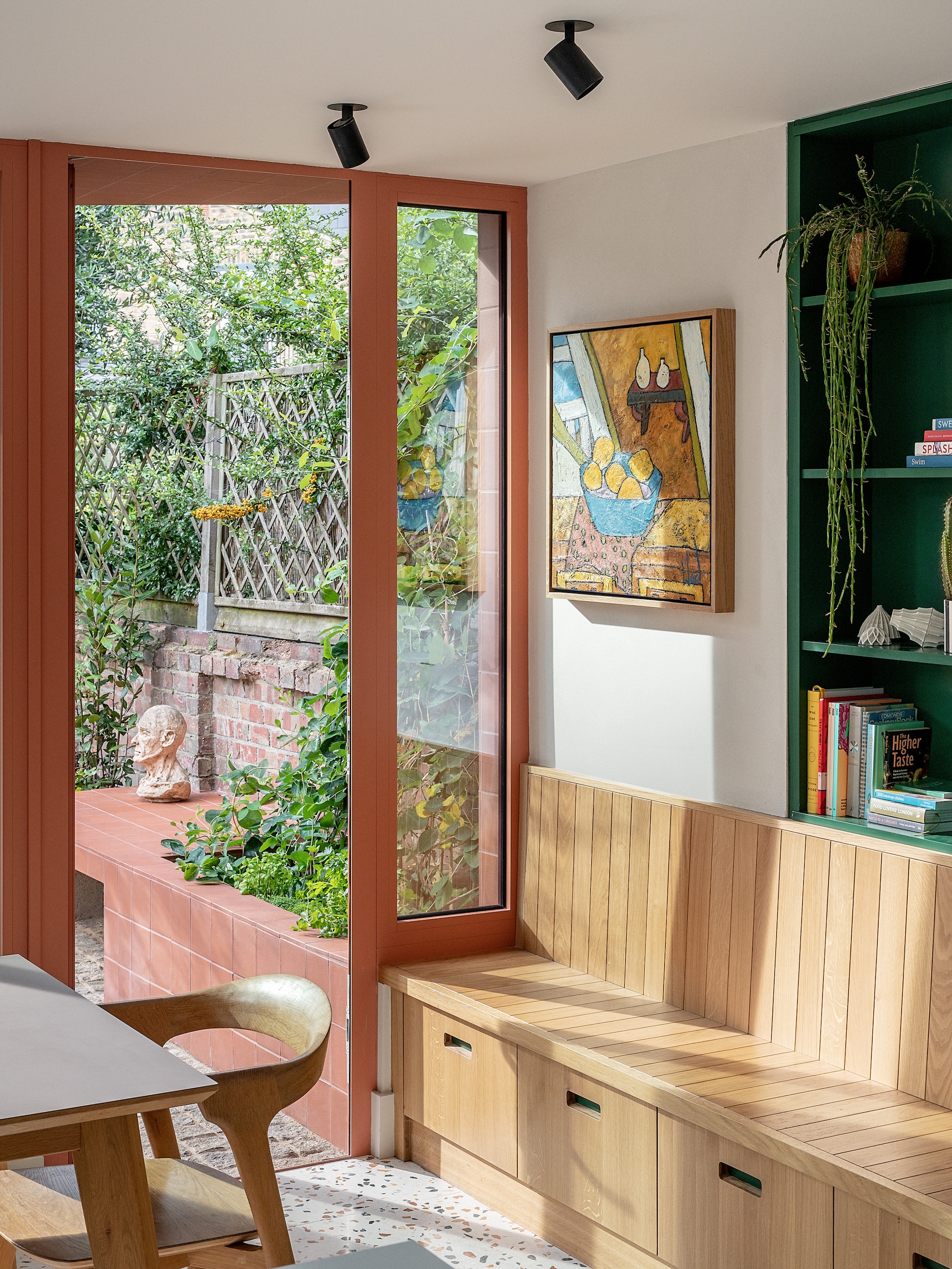 Sculptuur in de tuin gemaakt door Tess. Terracotta stenen hergebruikt. Eikenhouten bank met opbergruimte gemaakt door meubelmaker James Dowie. Schilderij Johanna Ward. vtwonen 02-2026 | fotografie Taran Wilkhu | productie Living Inside