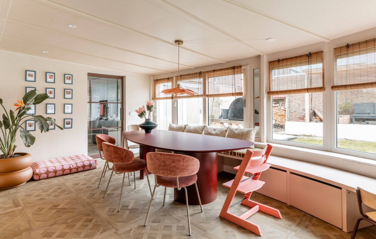 De bamboe jaloezieën en vloer met Versailles-patroon van Aanhuis.nl zorgen voor warmte in de eethoek.