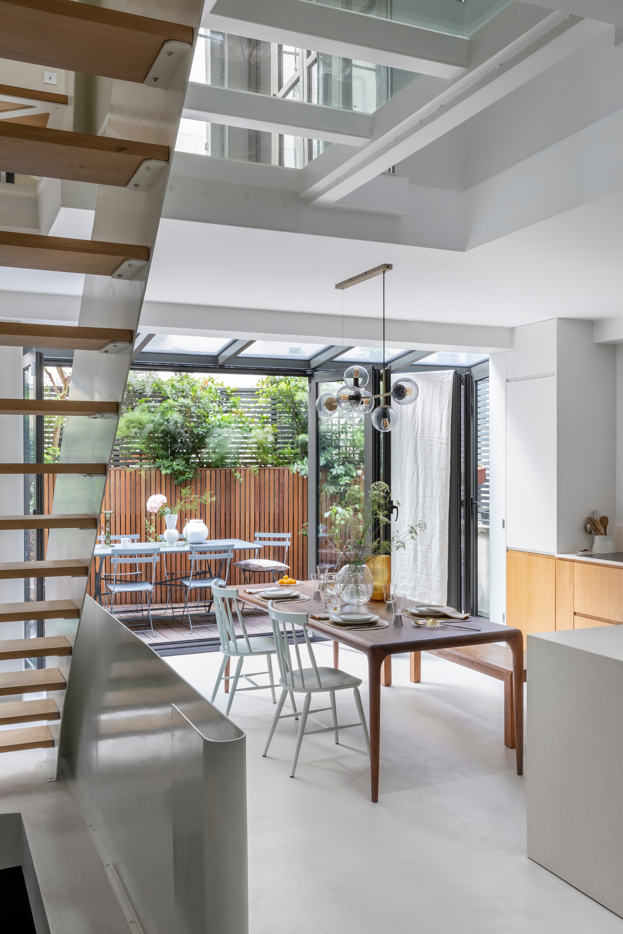 Tafel Artisan. Stoelen Landmade. Lamp Orb van Bolia. Muurkleur Strong White van Farrow & Ball. Terrastafel en stoelen Fermob.  vtwonen 02-2026 | styling Camille Hermand | fotografie Pauline Le Goff | productie AC Scoffoni