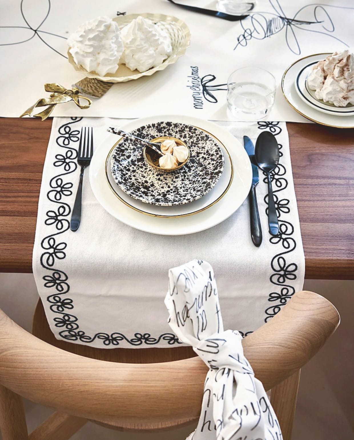 vtwonen bord, porselein, wit, 35,5 cm (Ø) € 44,95, bord, porselein, wit-goud, 25,5 cm (Ø) € 14,95 of als set van 2 € 25,-, theetip, porselein, goud, 7 cm (Ø) set van 4 € 14,95, bestekset, matzwart, 18-delig € 89,- (shop.vtwonen.nl). Xenos gebaksbord, gespikkeld zwart-wit, 18x2,2 cm (Øxh) € 3,99, lepel, gespikkeld zwart-wit, 12,7 cm (l) € 2,49 (xenos.nl). Arket tafelloper, geborduurd katoen, 140x40 cm (lxb) € 29,-, serveerschaal, metaal, beige € 13,- (arket.com). Doing Goods taartschep met gouden strik, gerecycled messing, per set € 75,- (doing-goods.com). H&m home bord, porselein, zwart randje, 20 cm (Ø) € 4,99 (hm.com). Overig privébezit. Mica Decorations kandelaar Christy, alumnium, zwart, 23x23x44 (lxbxh) € 67,95 (shop.vtwonen.nl). Kulu Club placemat Wavy, katoen, wit, 48x38 cm (lxb), set van 2 € 26,95 (shop.vtwonen.nl). Oyoy schaal Toppu, keramiek, zwart, 13x4,5 cm (Øxh) € 29,- (shop.vtwonen.nl). vtwonen kerstspecial 2025 | styling Sanne Ketelaar | fotografie Alexander van Berge, Stan Koolen