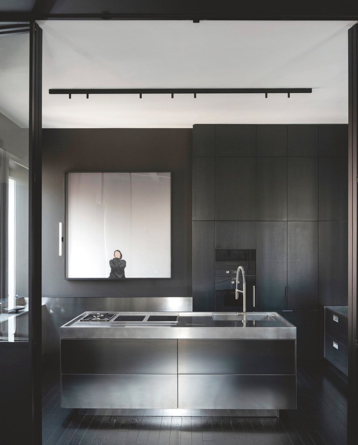 Keukeneiland van roestvrij staal van Arclinea. Op de zwart geverfde muur een werk van Marina Abramović via Galleria Lia Rumma. Stijlvol Wonen 10-2025 | fotografie Nathalie Krag | tekstbewerking Tanne Donjacour Gielen