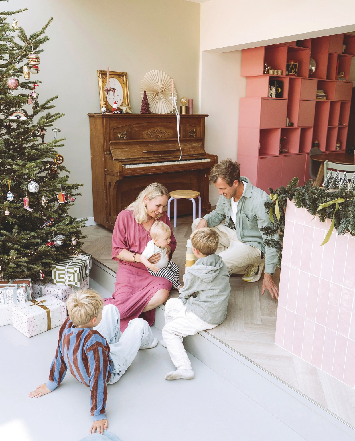 Kerstboomornamenten, souvenirs, cadeaus, piano Marktplaats. Schilderij op piano en kaarsenstandaard kringloop, daarin een zelfgetekende prent. Roze tegels Tegels in Huis. vtwonen 11-2025 | styling Sanne Ketelaar | fotografie Stories By Chriske