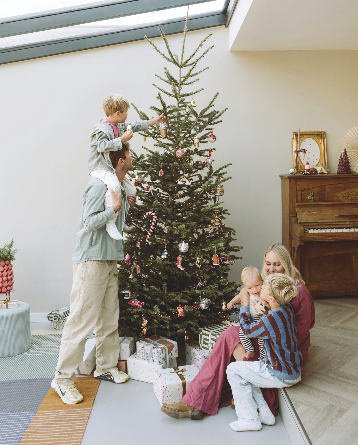 Kerstboomornamenten, souvenirs, cadeaus en piano Marktplaats. Schilderij op piano en kaarsenstandaard kringloop, daarin een zelfgetekende prent. Vloerkleed Wehkamp. vtwonen 11-2025 | styling Sanne Ketelaar | fotografie Stories By Chriske  | tekst Merel van der Lande