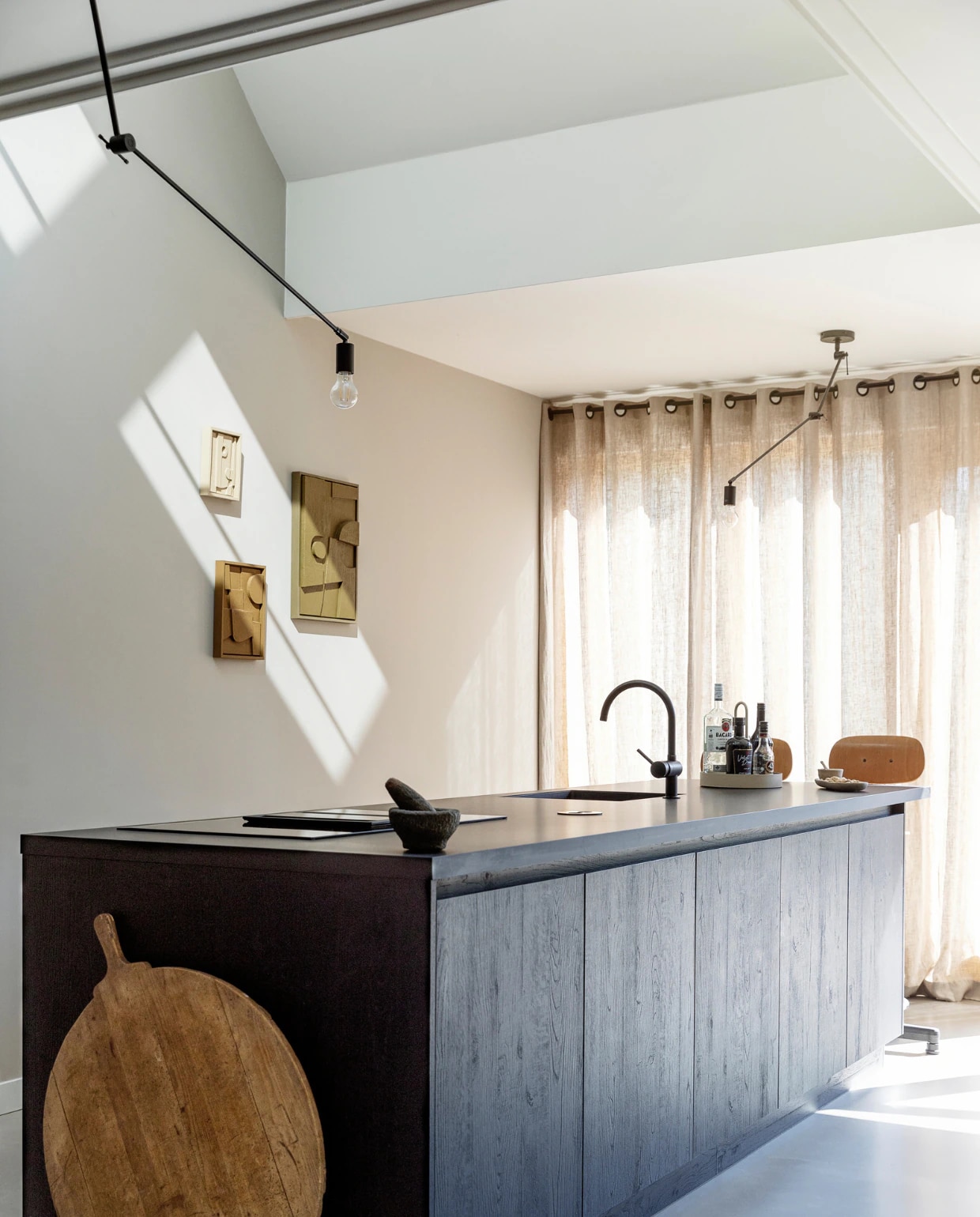 Keuken met Fenix keukenblad en spoelbak Huysinc. Kookplaat Siemens, barkrukken Marktplaats. Dienblad Grib van Ferm Living, schaaltjes Zara Home. Linnen gordijnen Femmie Naturel van Kwantum. Hanglampen Blitz van Qazqa, kunstwerken 3D Shapes van Edith Beurskens. Muurverf Mushroom van Lab Paint. Overig onbekend.