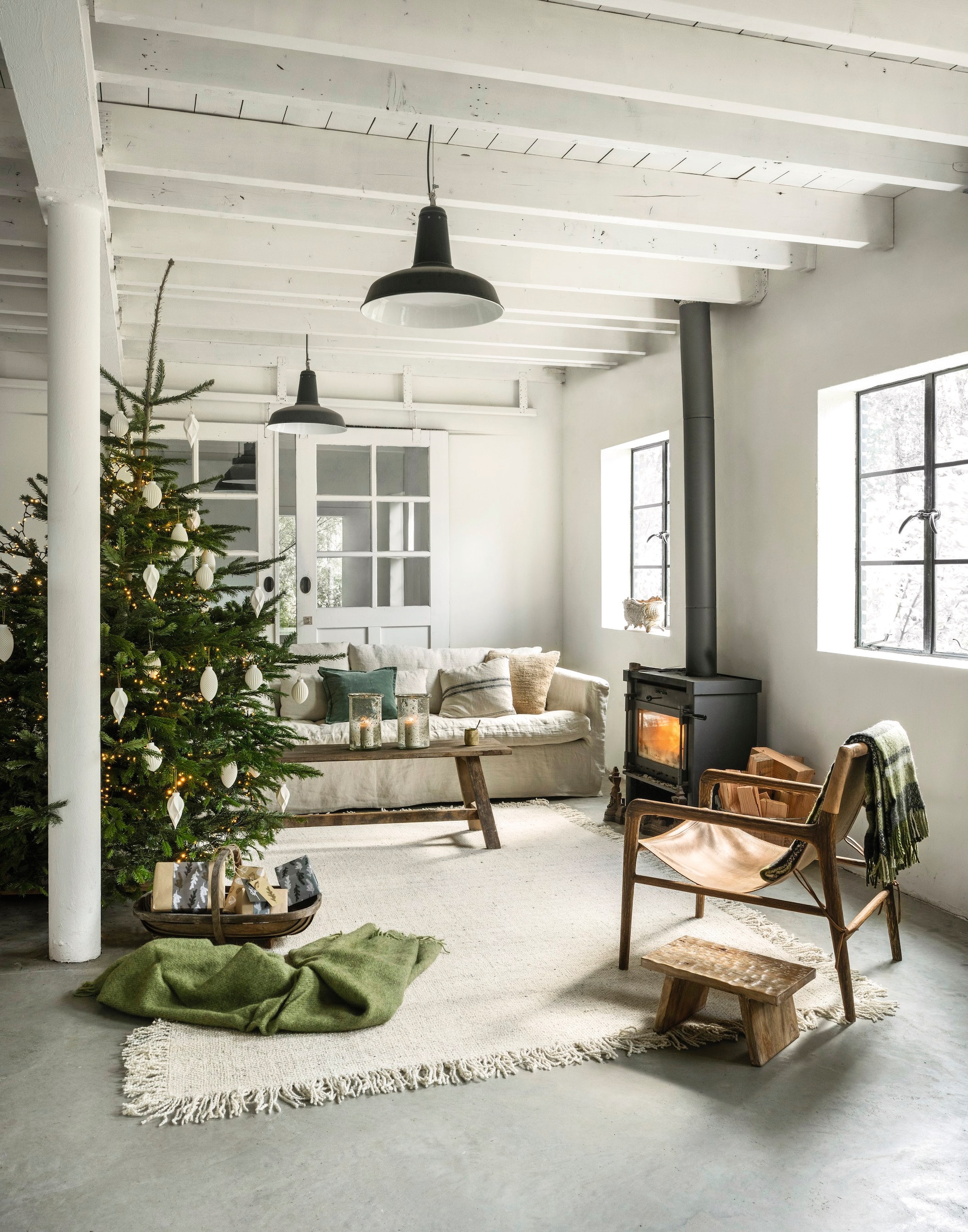 Loods 5 4-zitsbank Sintra, linnen, beige, 270x107x84 cm (lxbxh) € 3924,- (loods5.nl). Het Kabinet fauteuil, teak met buffelleer, bruin, 67x74x80 cm (bxdxh) € 839,-, vloerkleed Woolie, wol, crème, 290x200 cm (lxb) € 499,- (hetkabinet.nl). Aura Peeperkorn salontafel, teak, bruin, 160x40x45 cm (lxbxh) € 429,-, windlichten, glas € 89,95 (aurapeeperkorn.com). Klippan plaid Gotland pear, wol, groen € 95,-, Raw Materials kruk Chiseled top, mangohout, bruin, 40x25x20 cm (bxdxh) € 55,95, vtwonen kerstornament Waffle, porselein, wit € 9,95, kerstornament Diamond, porselein, wit € 8,95 en kerstornament Stripes, porselein, wit € 8,95, soortgelijke guirlande Triumph Tree guirlande Colorado, pvc, frosted green, 180 cm € 28,95 (shop.vtwonen.nl). Madam Stoltz kussensloop, katoen en fluweel, groen € 29,75 (deens.nl). Ilse van Stoltz mok Origin, keramiek, groen-wit € 30,- (ilsevanstoltz.com). Extra Vert mand, ijzer € 65,- (extravert.nl). Hanglampen, plukmand privébezit. vtwonen landelijk 11-2025 | styling Marianne Luning | fotografie Stan Koolen