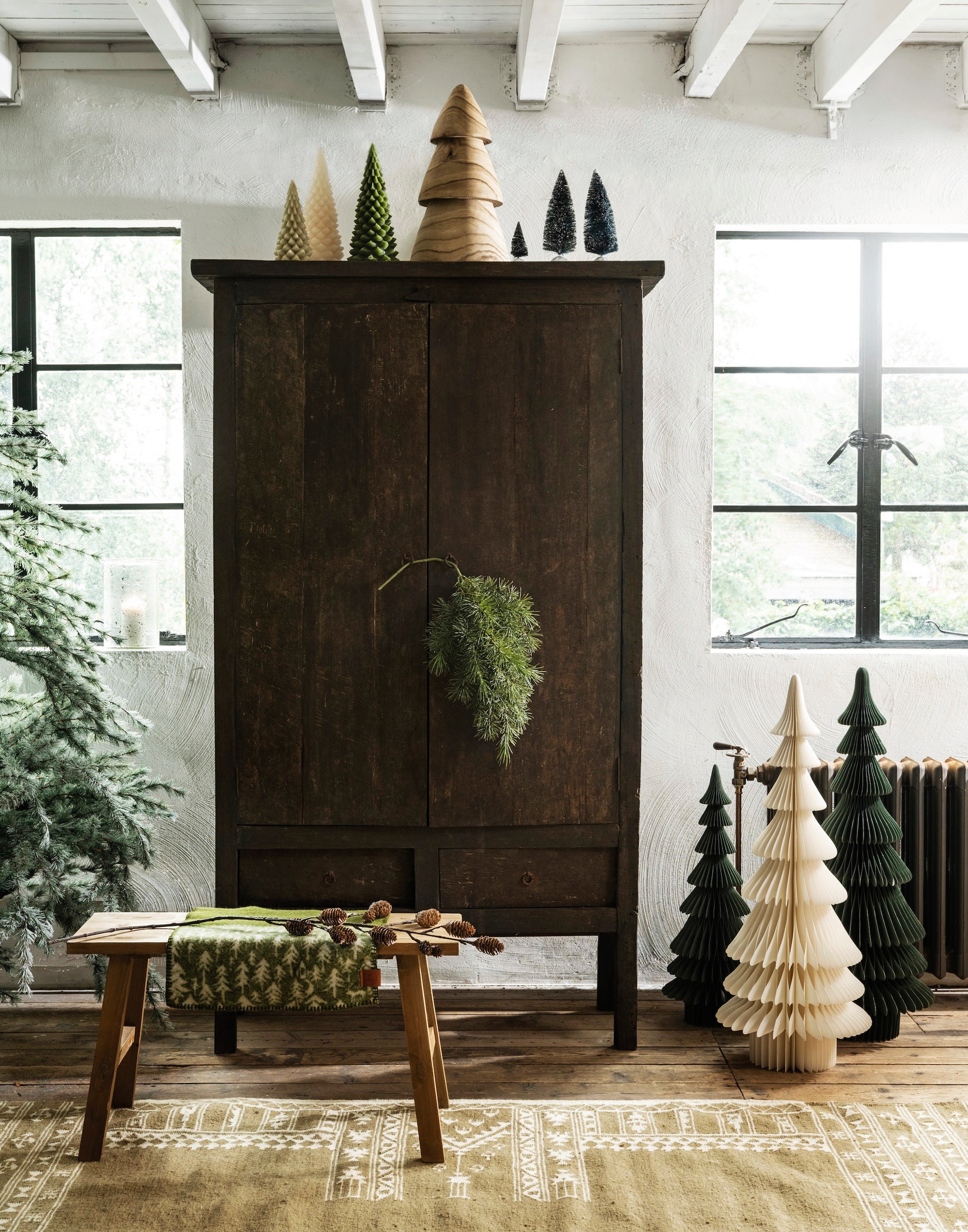 Aura Peeperkorn kast, oud teak, 112x50x190 cm (lxbxh) € 1695,-, windlicht, glas € 89,95 (aurapeeperkorn.nl). Mica Decorations bank Bold, gerecycled hout, bruin, 80x37x44 cm (lxbxh) € 114,95, Edelman kleine kerstbomen, kunststof, groen-wit set van 2 € 14,95, Sfeer voor jou kerstboom Springdale, groen-wit, kunststof € 260,- (shop.vtwonen.nl). Rustik Lys kerstboomkaarsen small, waxine, groen, vanaf € 4,95 (rustiklys.nl). Madam Stoltz vloerkleed, wol en katoen, khaki en gebroken wit, 230x160 cm (lxb) € 427,25, kerstboom, hout, bruin € 31,-, kerstbomen, papier, wit-groen, m/l € 48,25 en € 69,- (madamstoltz.dk). Mr. Plant takken, kunststof, groen vanaf € 25,- (deens.nl). vtwonen landelijk 11-2025 | styling Marianne Luning | fotografie Stan Koolen