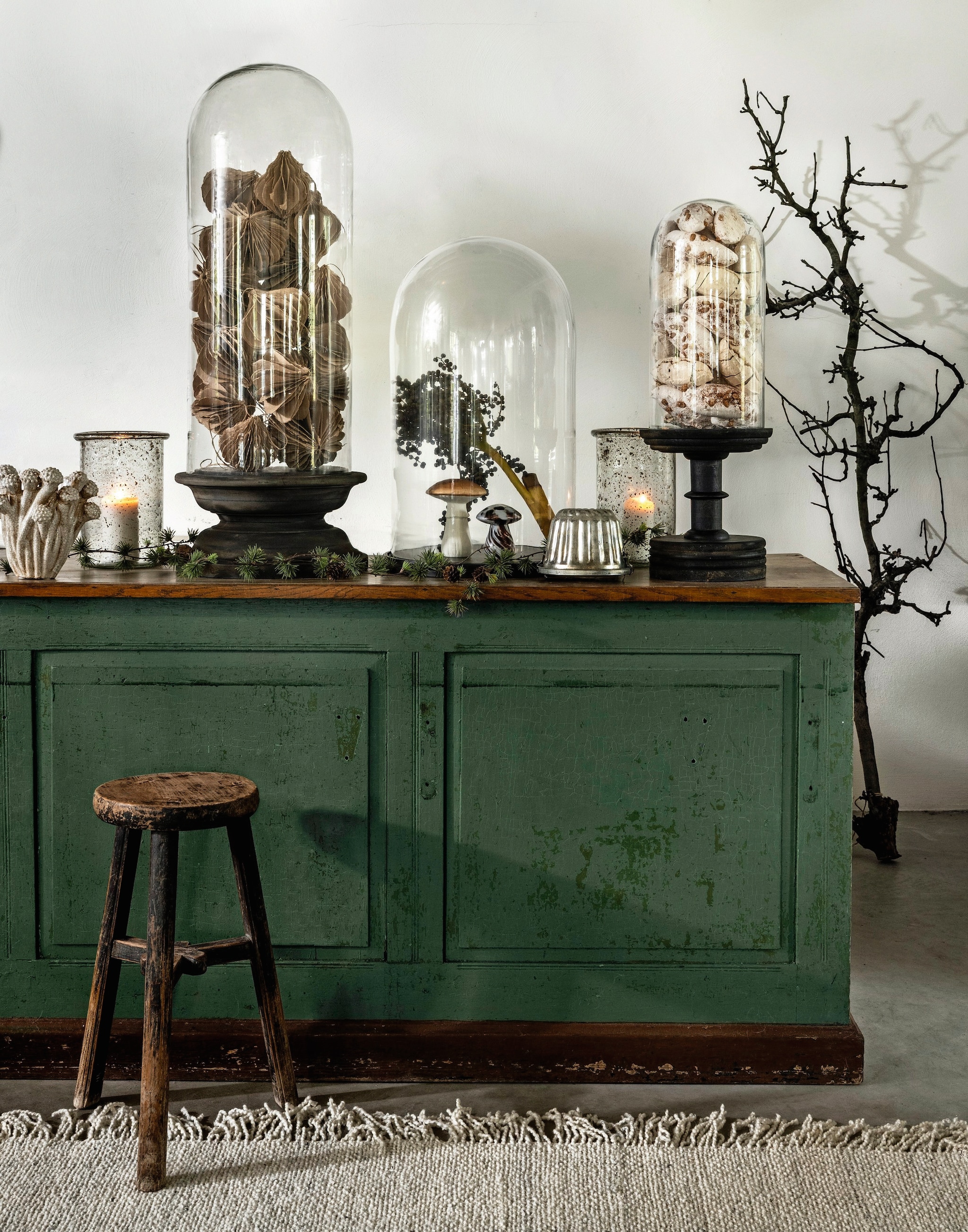 Van Dijk & Ko toonbank, hout, groen, 200x80x90 cm (lxbxh) € 600,- (vandijkenko.nl). Het Kabinet vloerkleed Woolie, wol, crème, 290x200 cm (lxb) € 499,-, kruk, onbehandeld hout, bruin € 149,-, stolp zonder voet, glas € 162,50 (hetkabinet.nl). Aura Peeperkorn stolpen met voet, glas en hout, transparant-bruin € 169,95 en € 339,95, windlichten, glas € 89,95 (aurapeeperkorn.nl). Nordal, vaas Funghi, keramiek, gebroken wit € 74,25 (nordal.com). Madam Stoltz, hangornamenten honeycomb (in stolp), papier, bruin, set van 2 € 15,25, paddenstoel Glass mushroom, glas, bruin-wit € 8,25(madamstoltz.dk). J-line paddenstoel, aardewerk, wit-bruin, set van 2 € 24,30 (shop.vtwonen.nl). Mister Plant guirlande € 31,25 (deens.nl). Meringues Sisters scooped meringues, per stuk vanaf € 2,15 (meringuesisters.nl). Bakvorm, tak privébezit. vtwonen landelijk 11-2025 | styling Marianne Luning | fotografie Stan Koolen