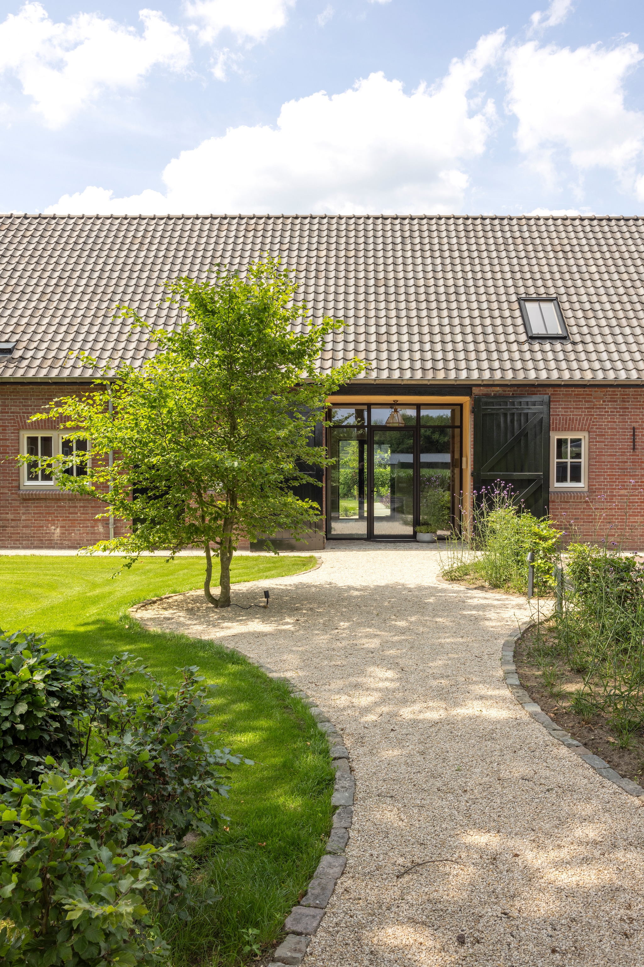 Deur Vts Aluminium. Pad van castle grind 5-8 mm. Boom: meerstammige beuk. vtwonen Landelijk 03-2026 | fotografie Anneke Gambon