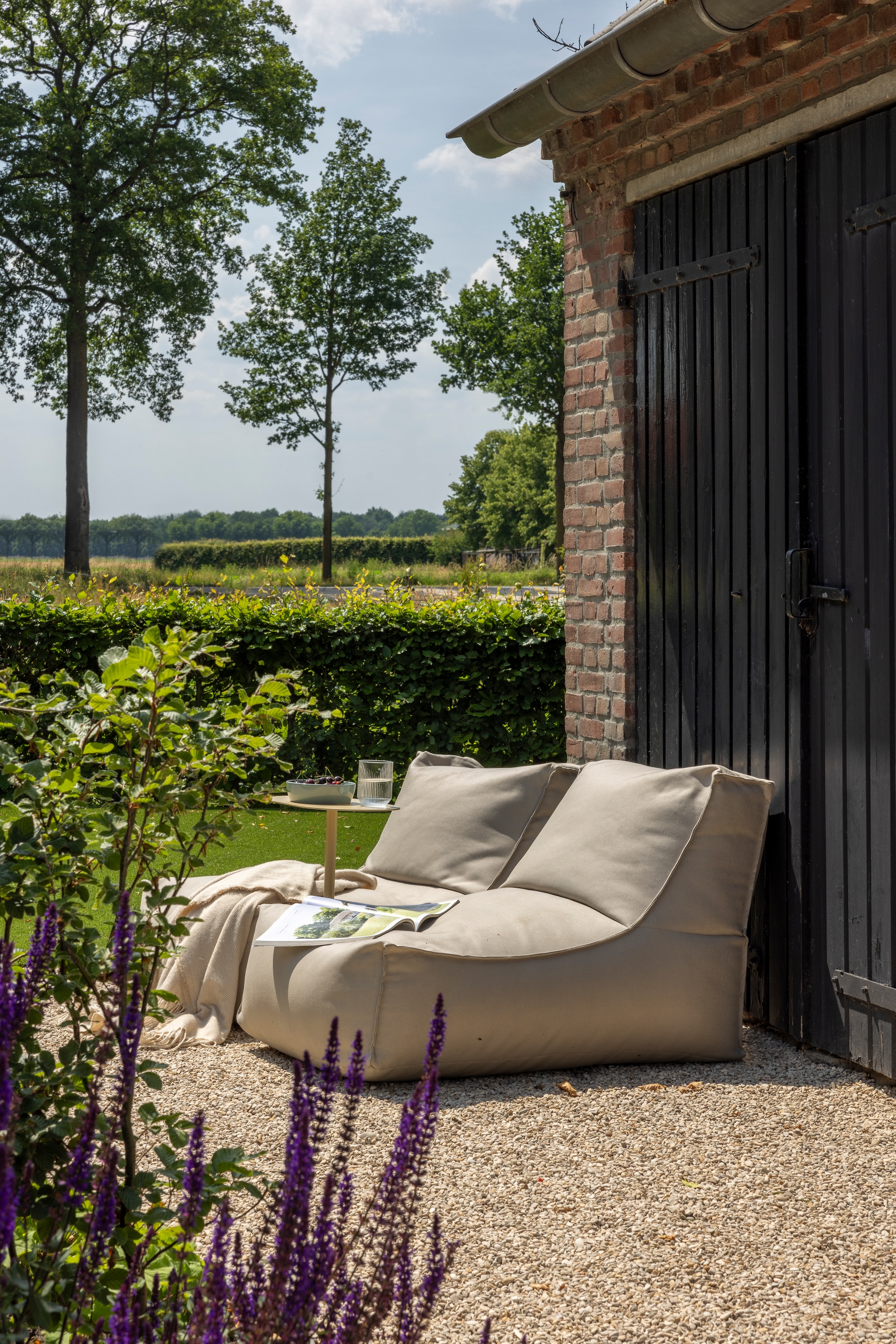 Loungestoelen Rock Korfu Outdoor van Ikwilzitzakken. Kleur op deur Oirschots monumentaal groen. Kunstgras Garden Sense Kunstgras. In dit deel van de tuin ligt kunstgras, omdat het functioneert als speeltuin met trampolines. vtwonen Landelijk 03-2026 | fotografie Anneke Gambon