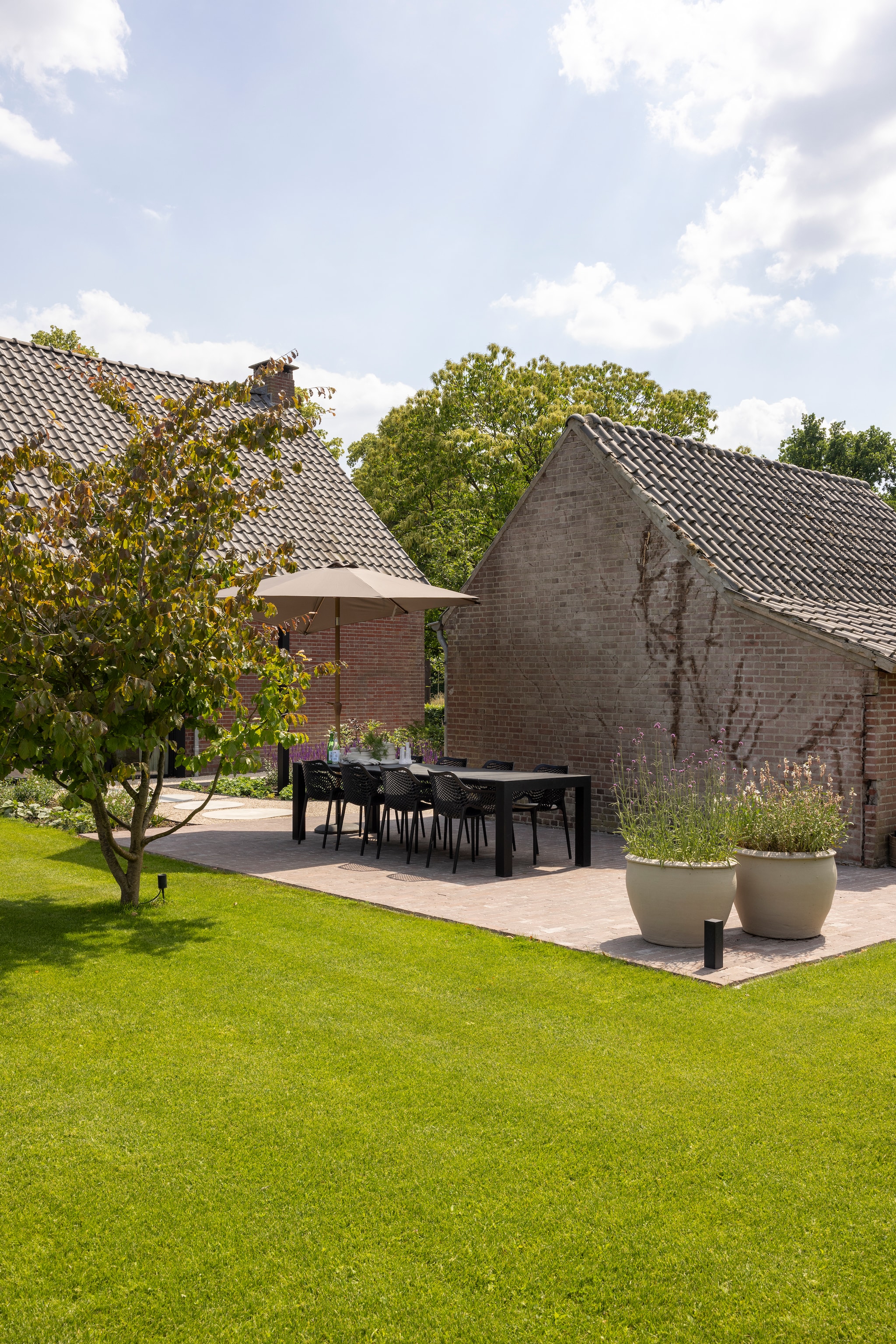 De stenen van het terras lagen oorspronkelijk in de boerderij en zijn buiten hergebruikt. Potten geschilderd met muurverf. vtwonen Landelijk 03-2026 | fotografie Anneke Gambon