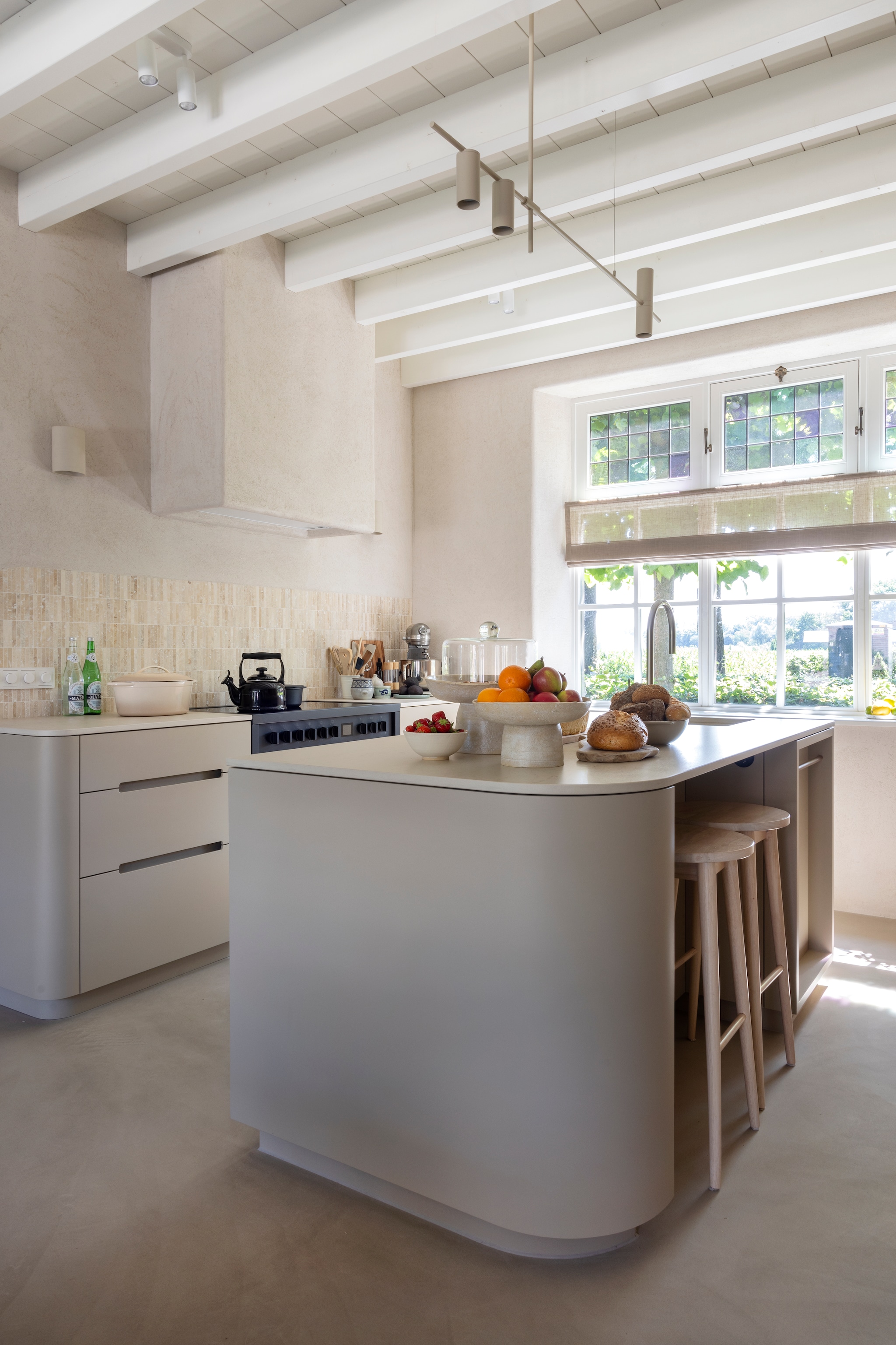 Keuken maatwerk door Storimans Interieur. Krukken Sakari. Fornuis Enfasi All Black van Steel Cucine. In de koof afzuigkap 821 white van Novy. Hanglamp Cassandra van Westwing. Spots Kwantum. Fruitschalen Atelier Ikigai. Vouwgordijn Navajo 218442 van Raamstyling. Wandtegels Travertin Kitkat van Meisjes van Steen. Muur leemstuc met leemfinish met toegevoegd stro kleur Kolumba Grau van Yosima. vtwonen Landelijk 03-2026 | fotografie Anneke Gambon