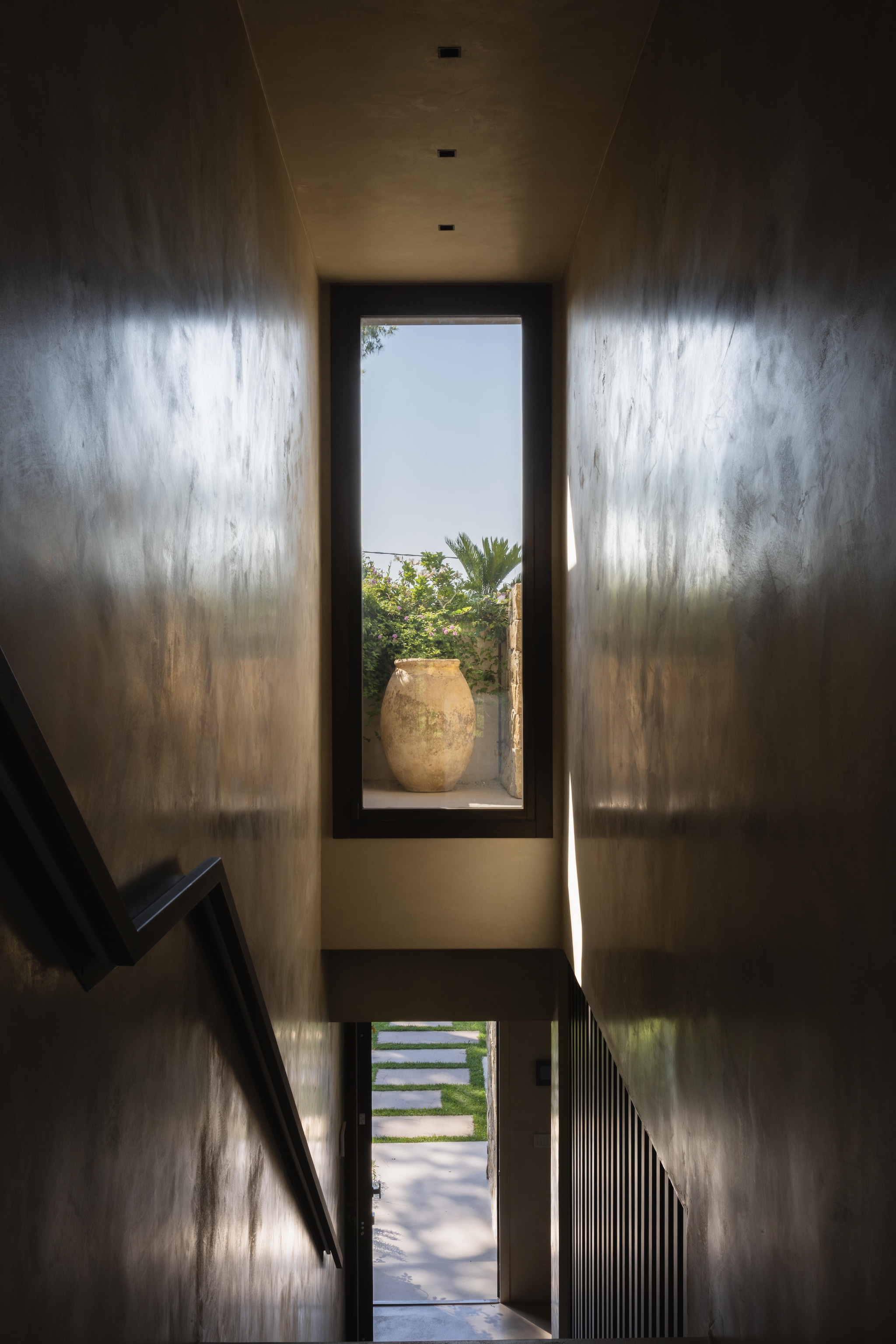 Doorkijkje vanuit het trappenhuis op de eerste verdieping. Een verticale raampartij accentueert de kalkafwerking van de wanden. vtwonen Design 02-2026 | Fotografie Monica Spezia | Productie Living Inside